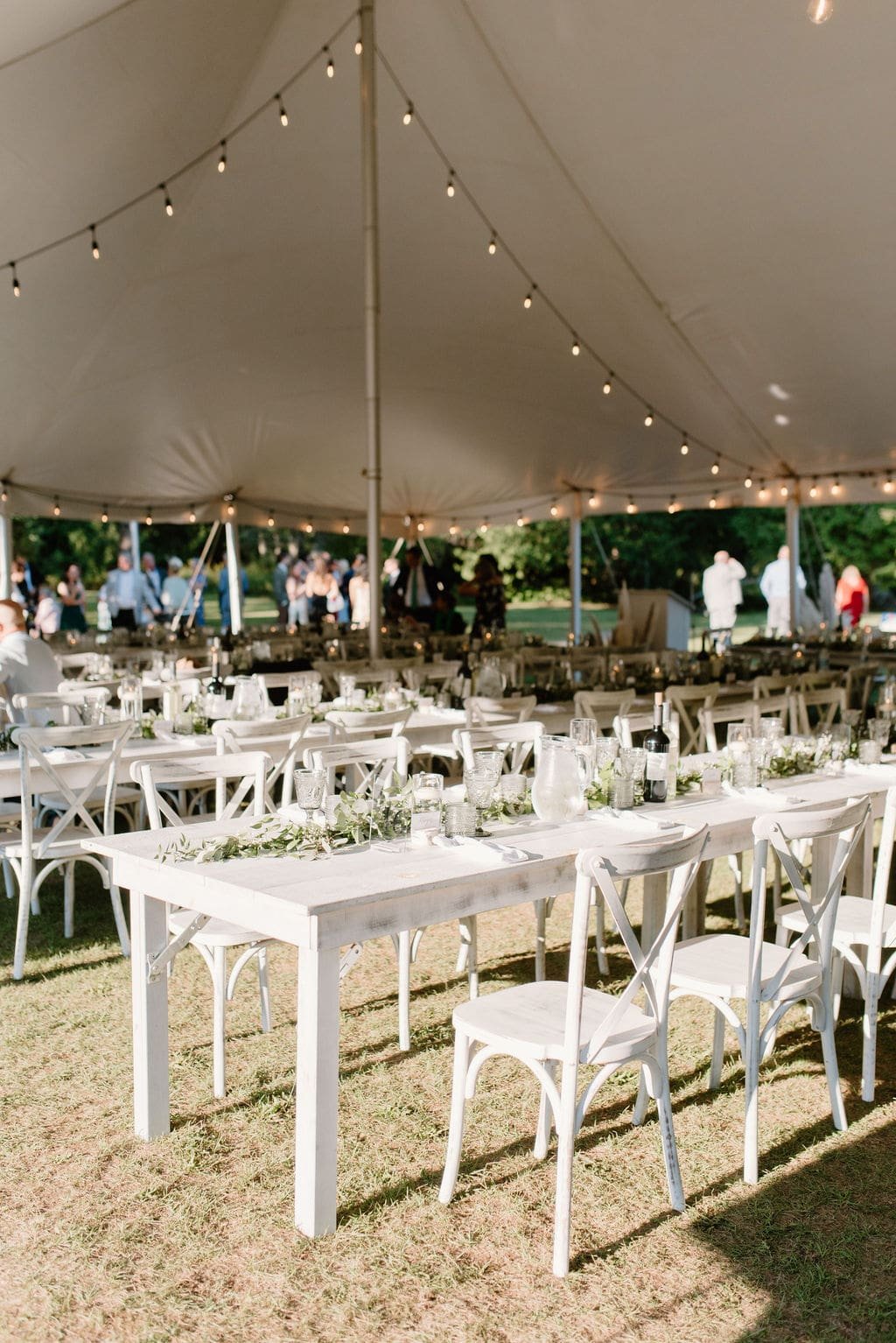 Tented wedding reception decor with white wood tables and chairs