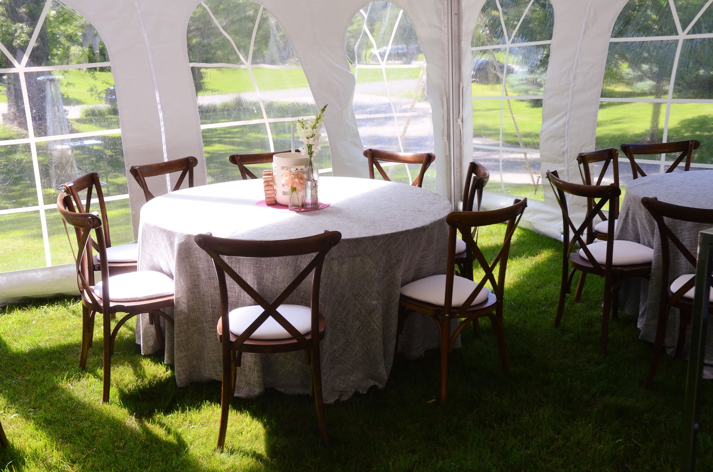 Wedding reception tables with wood chairs in a tent