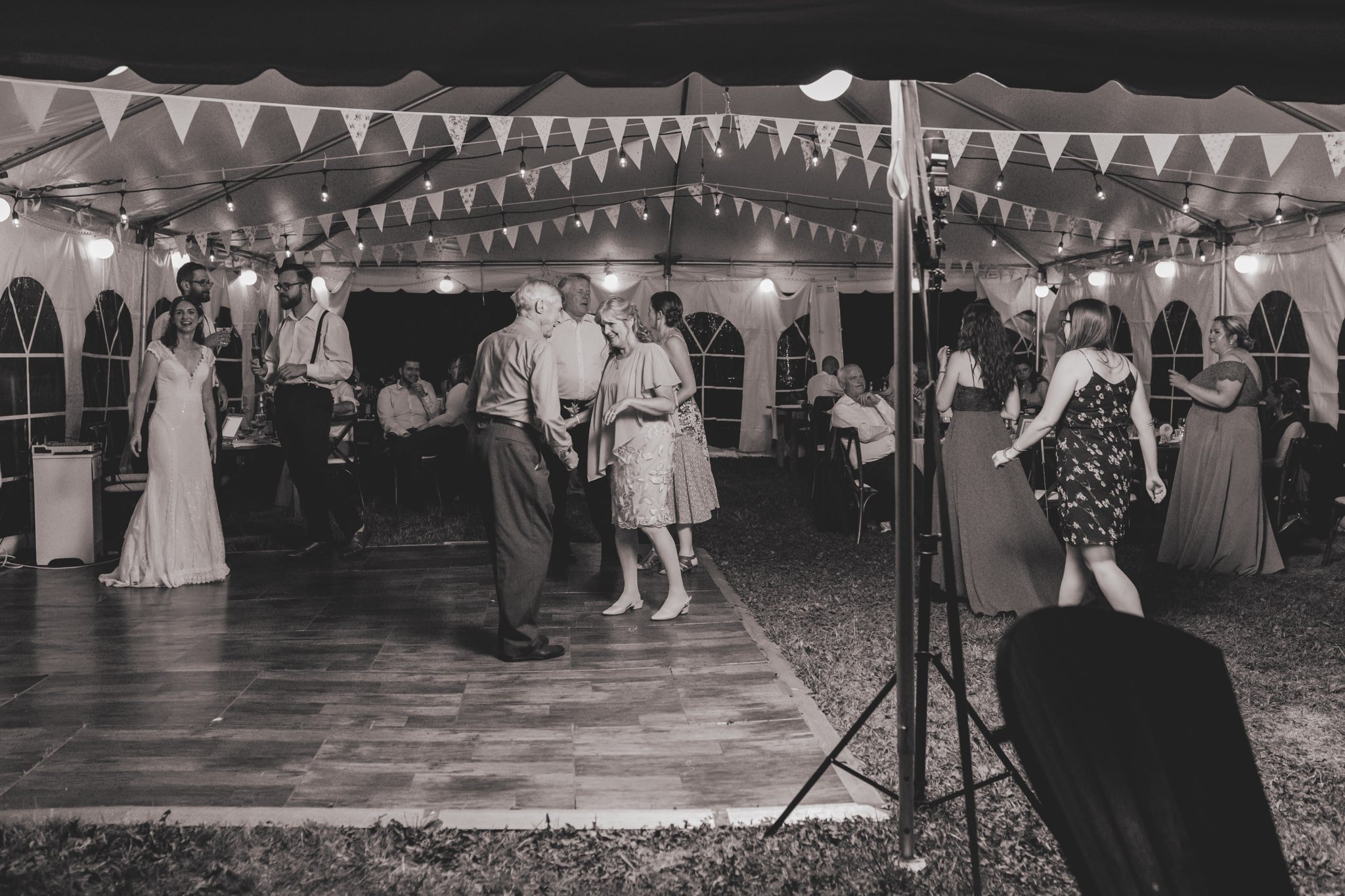 Guests dancing on dance floor at tented wedding reception