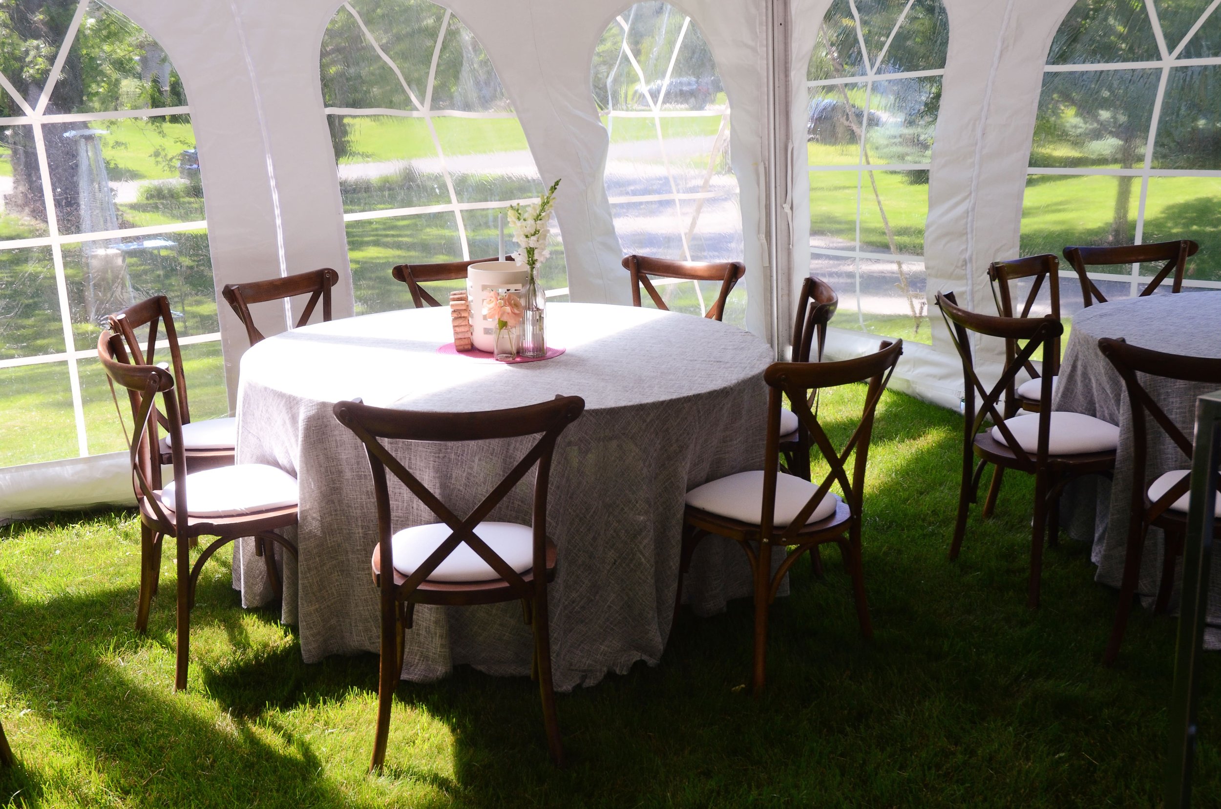 Backyard tented wedding reception table with linens and wood chairs