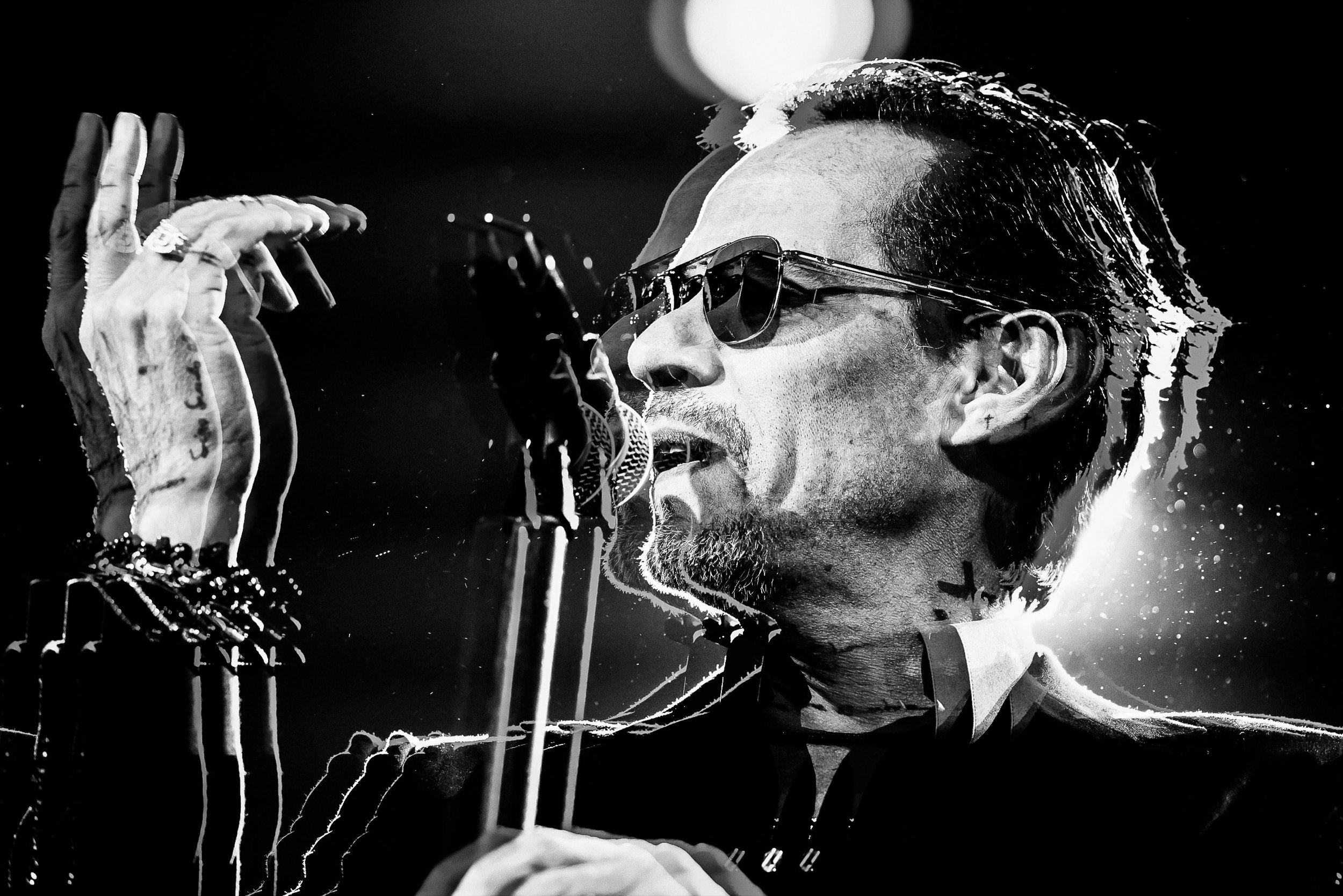 Marc Anthony captivates the audience with a mesmerizing performance at the Frost Bank Center in San Antonio, Texas. This black-and-white photograph, captured by music photographer Chris Stokes, highlights the artist's emotive expression and commandin