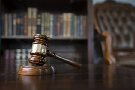 148849475-judge-office-gavel-on-brown-shining-table-and-collection-of-legal-books-in-the-bookshelf-.jpg