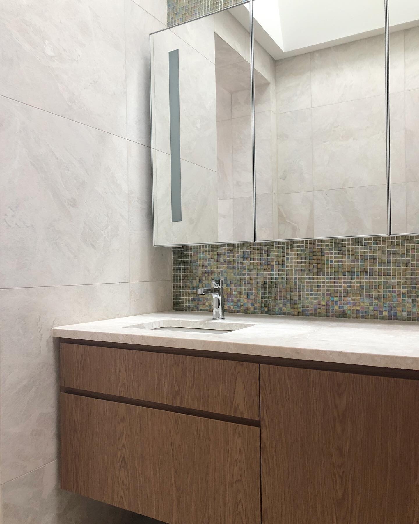 Floating timber veneer vanity with sharks nose finger-pull handles. Glass shaving cabinet with sandblasted light diffuser #sublimecustomcabinetry #customjoinery #ensuite