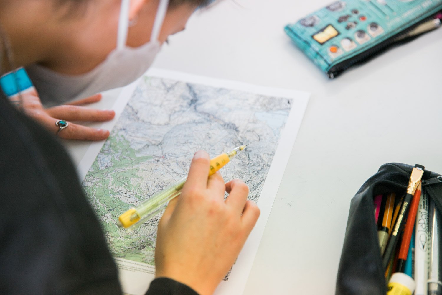 A student examines a topographical map and traces water runoff