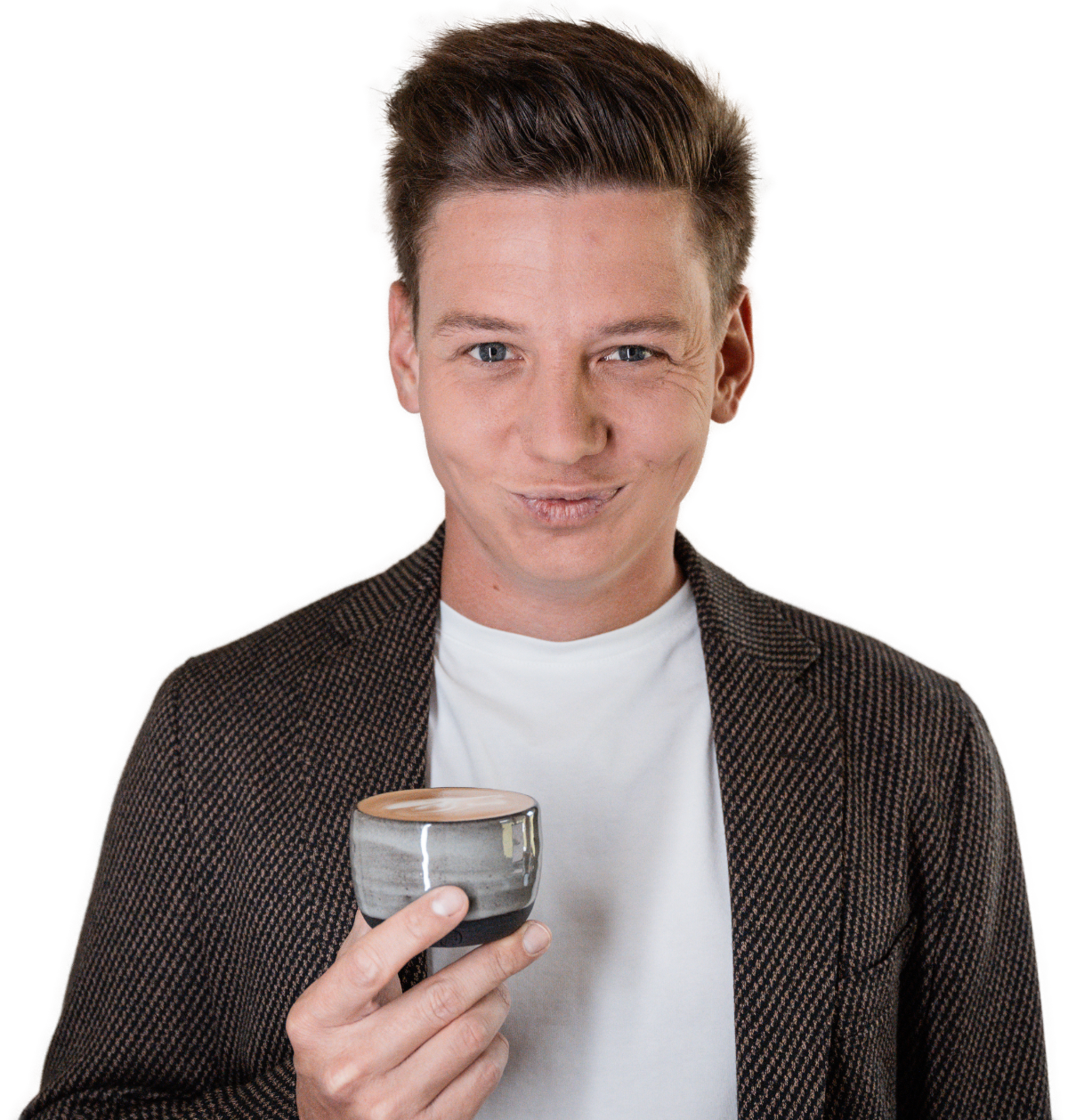 Sebastian Schmidt mit braunen Haaren, trägt ein kariertes Jackett und eine weiße T-Shirt, hält eine Schale mit Kaffee und schaut in die Kamera, macht einen Augenzwinkern.