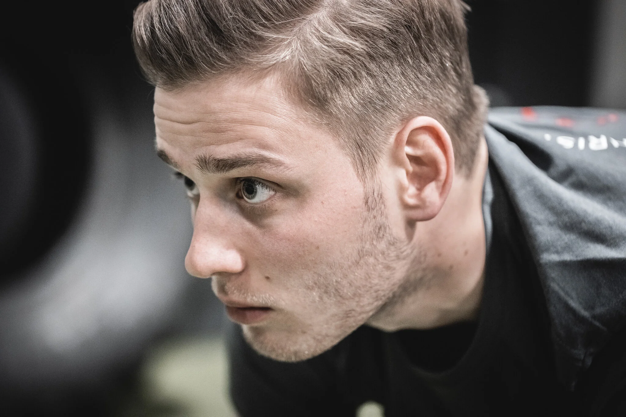 Nahaufnahme eines jungen Mannes mit kurzen, braunen Haaren, der nach unten schaut.