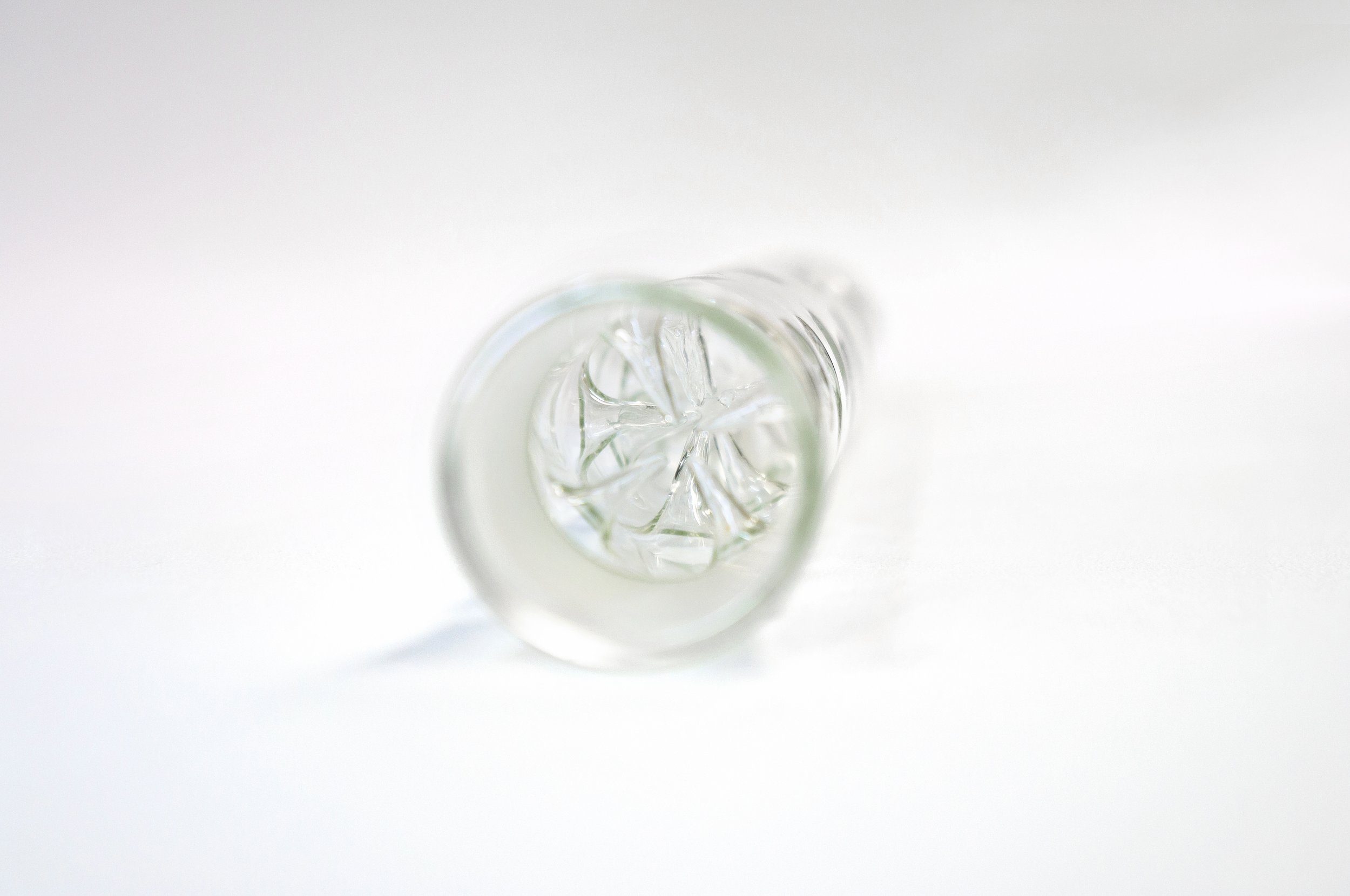 Close-up of an empty, clear glass vase with a textured base on a white background.