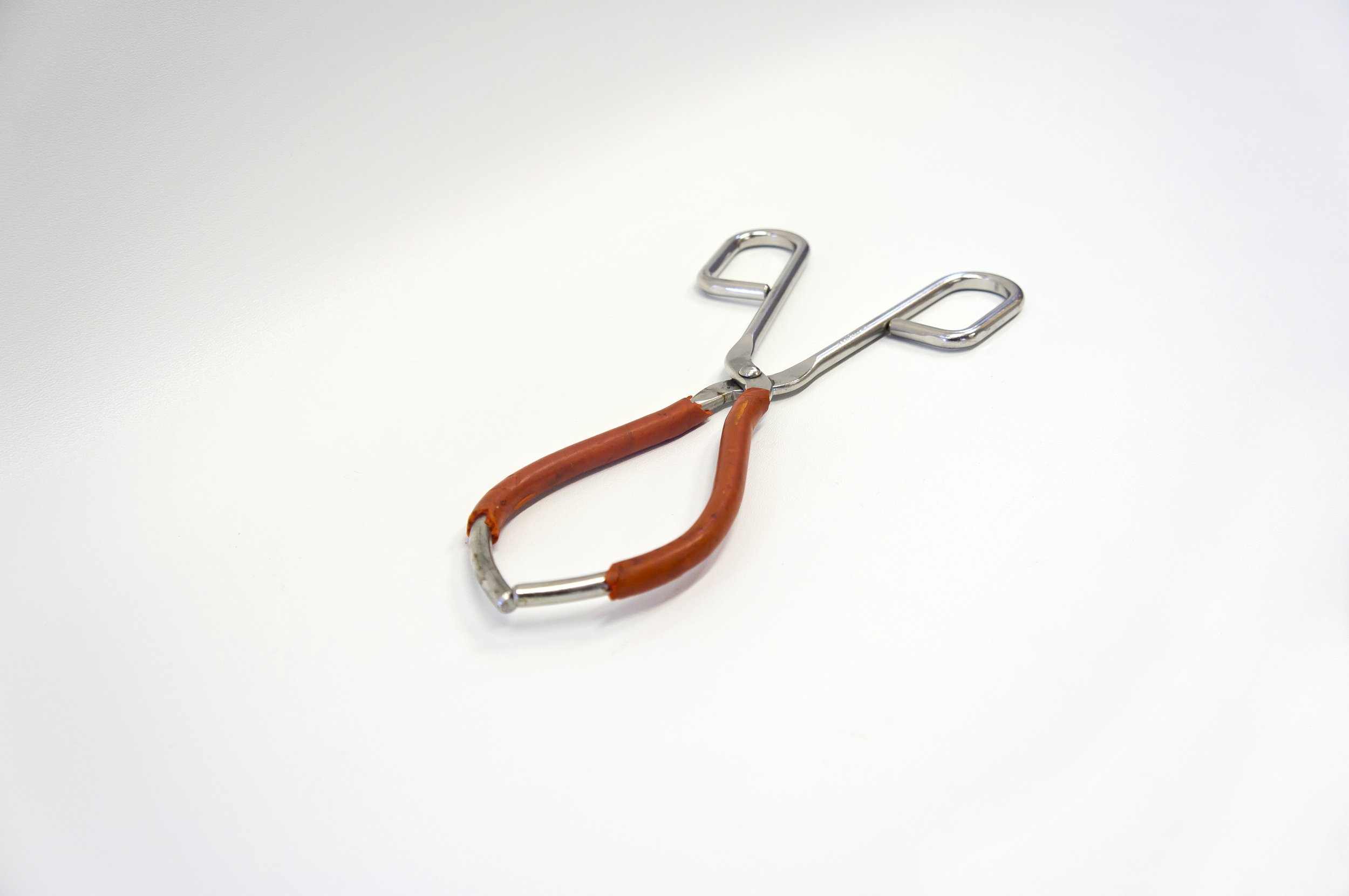 Metal kitchen tongs with red rubber grips on a white background.