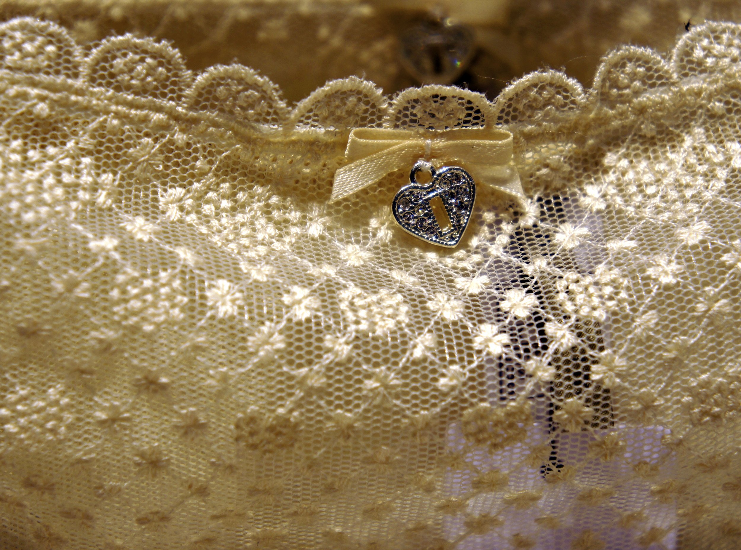 Close-up of lace fabric with a decorative heart charm attached.