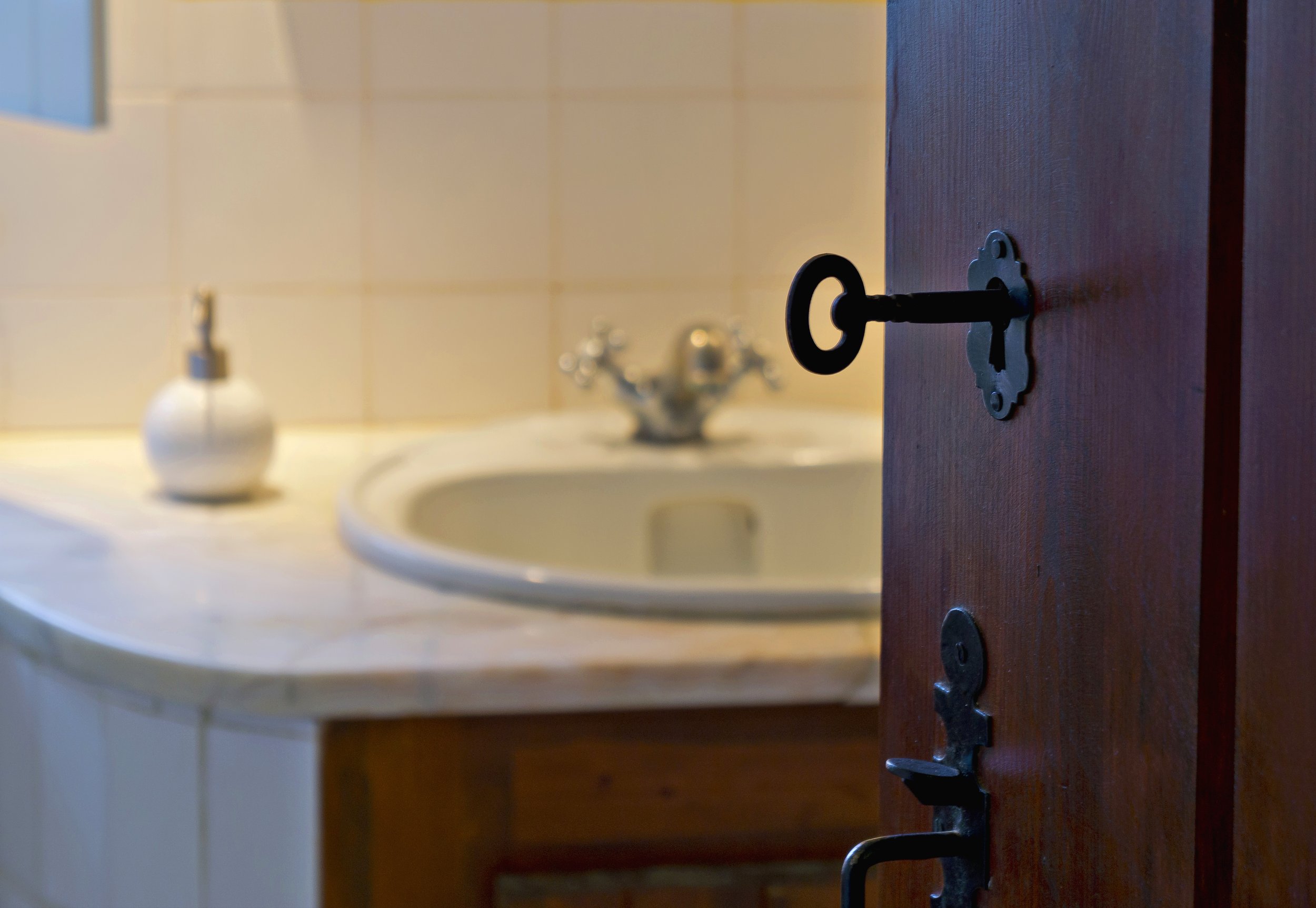 Old-fashioned key in wooden door, bathroom sink