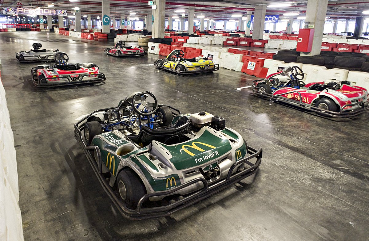 Indoor go-kart track with five parked karts featuring branded liveries.