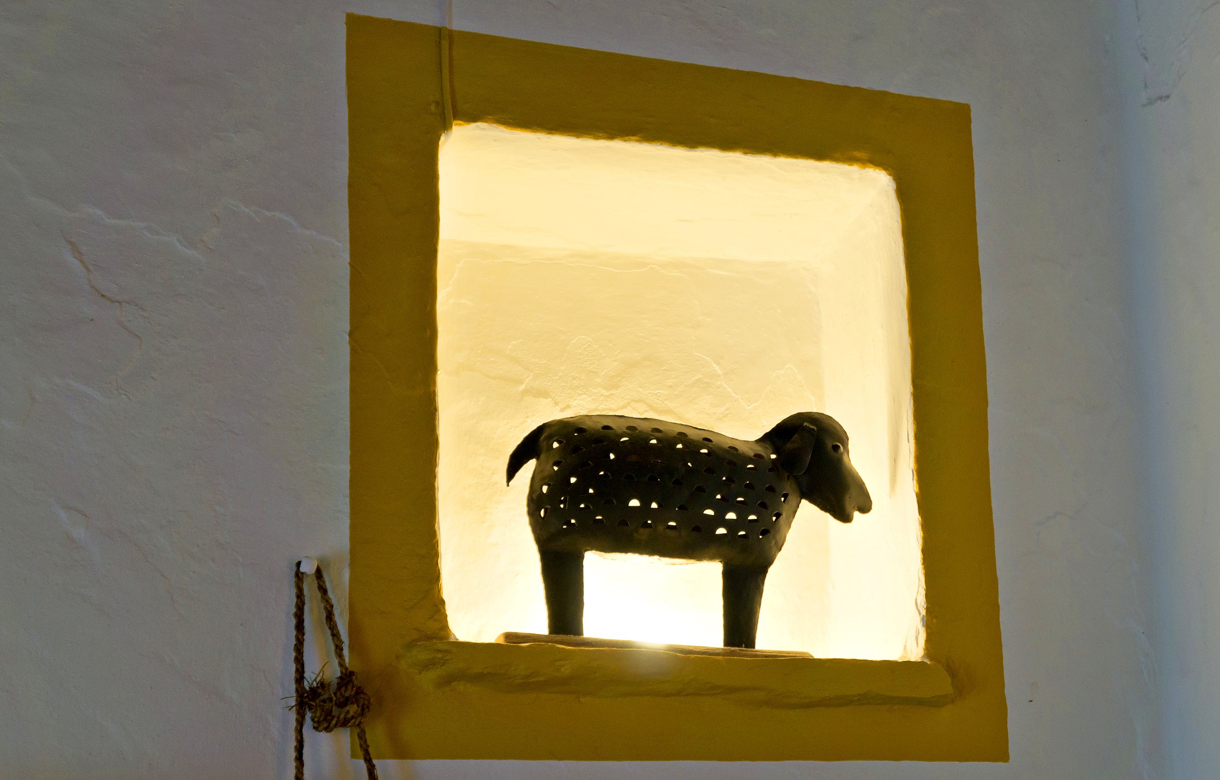 Decorative black sheep figurine in a lit alcove with a yellow border