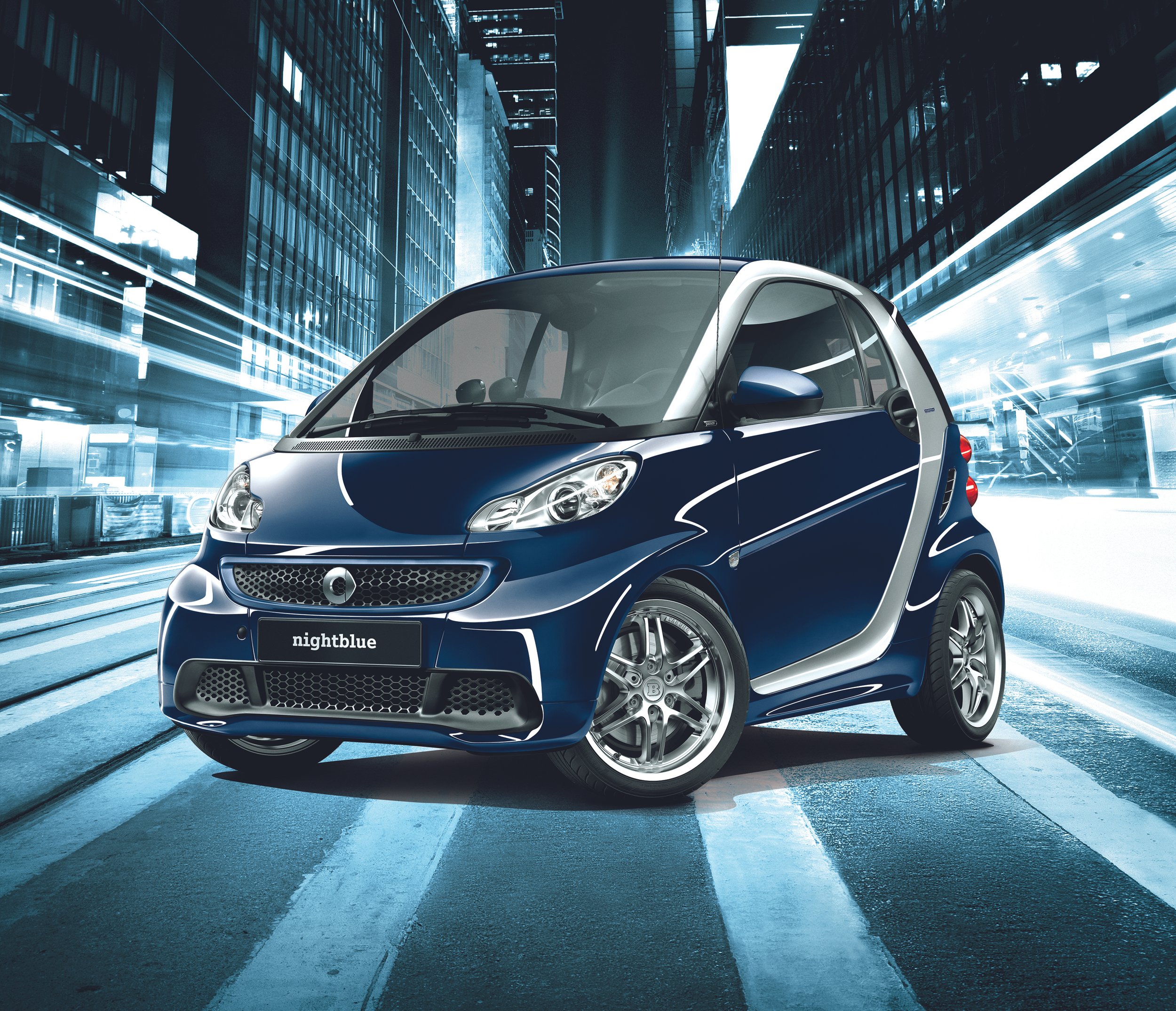 Blue Smart car in futuristic cityscape with motion blur lights at night.