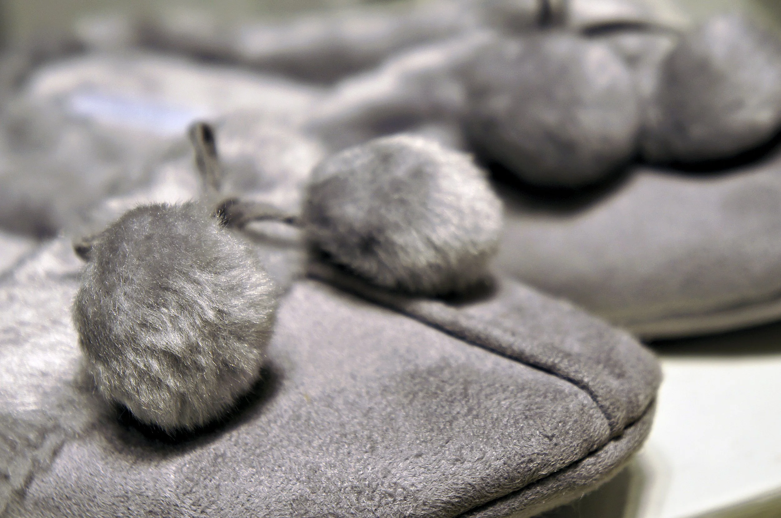 Close-up of gray fuzzy slippers with pom-poms