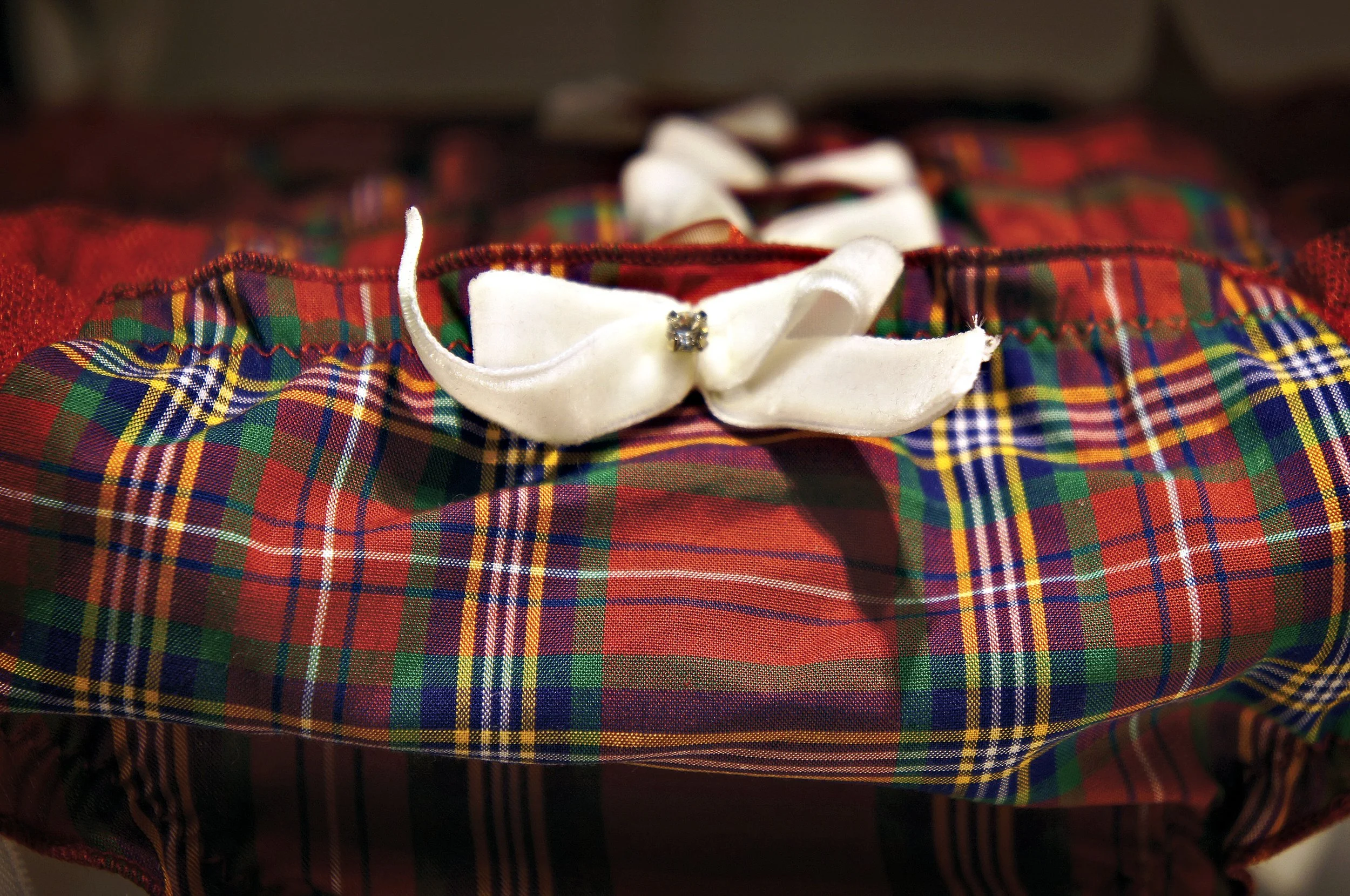 Close-up of red and green plaid fabric with a white bow