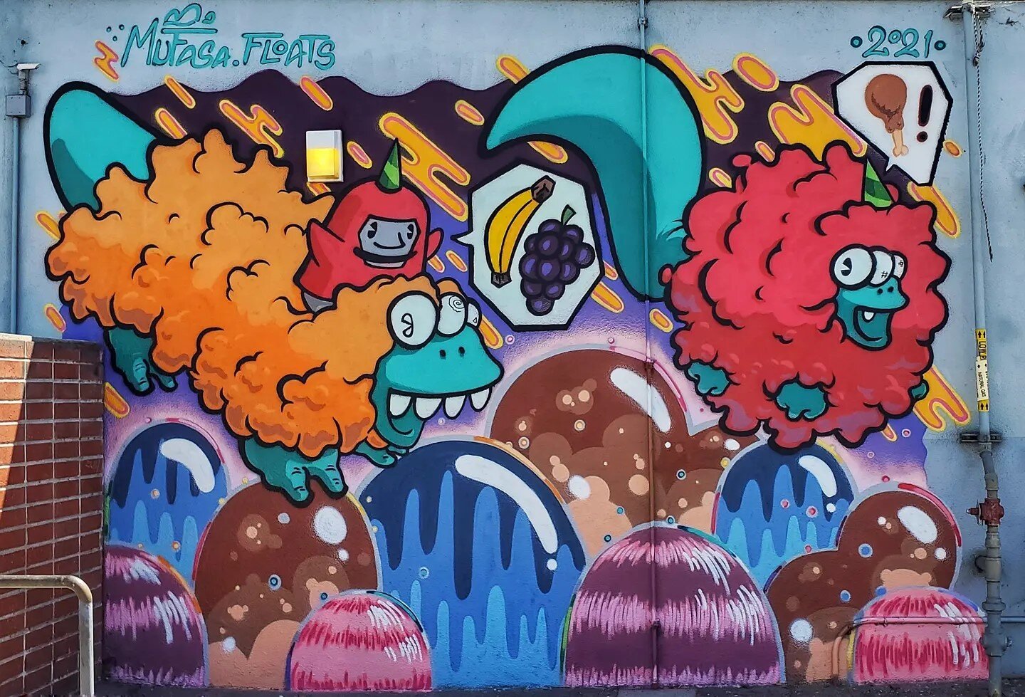 🔥🎉💥This rad, energetic mural by @mufasa.floats is painted on the school's cafeteria and playfully incorporates various foods throughout, and features his recognizable Suarley character 🍇🍌🎨!! 

📣 And big thanks to our sponsors @giphyarts 🦠 @ko