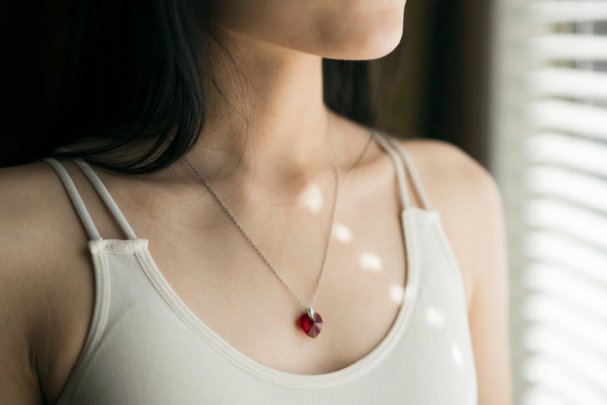 woman wearing a simple necklace with a red stone