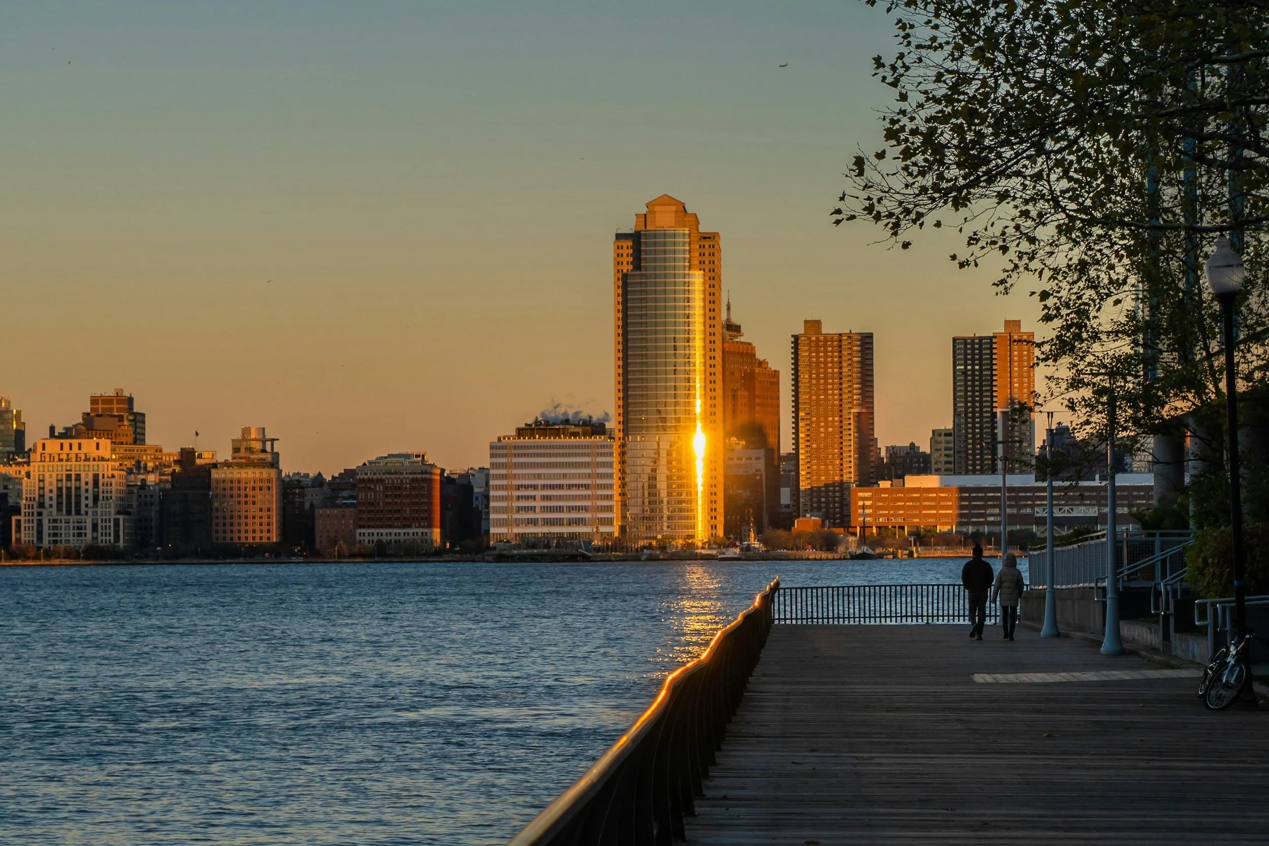 Jersey City skyline at dusk with couple walking along the river