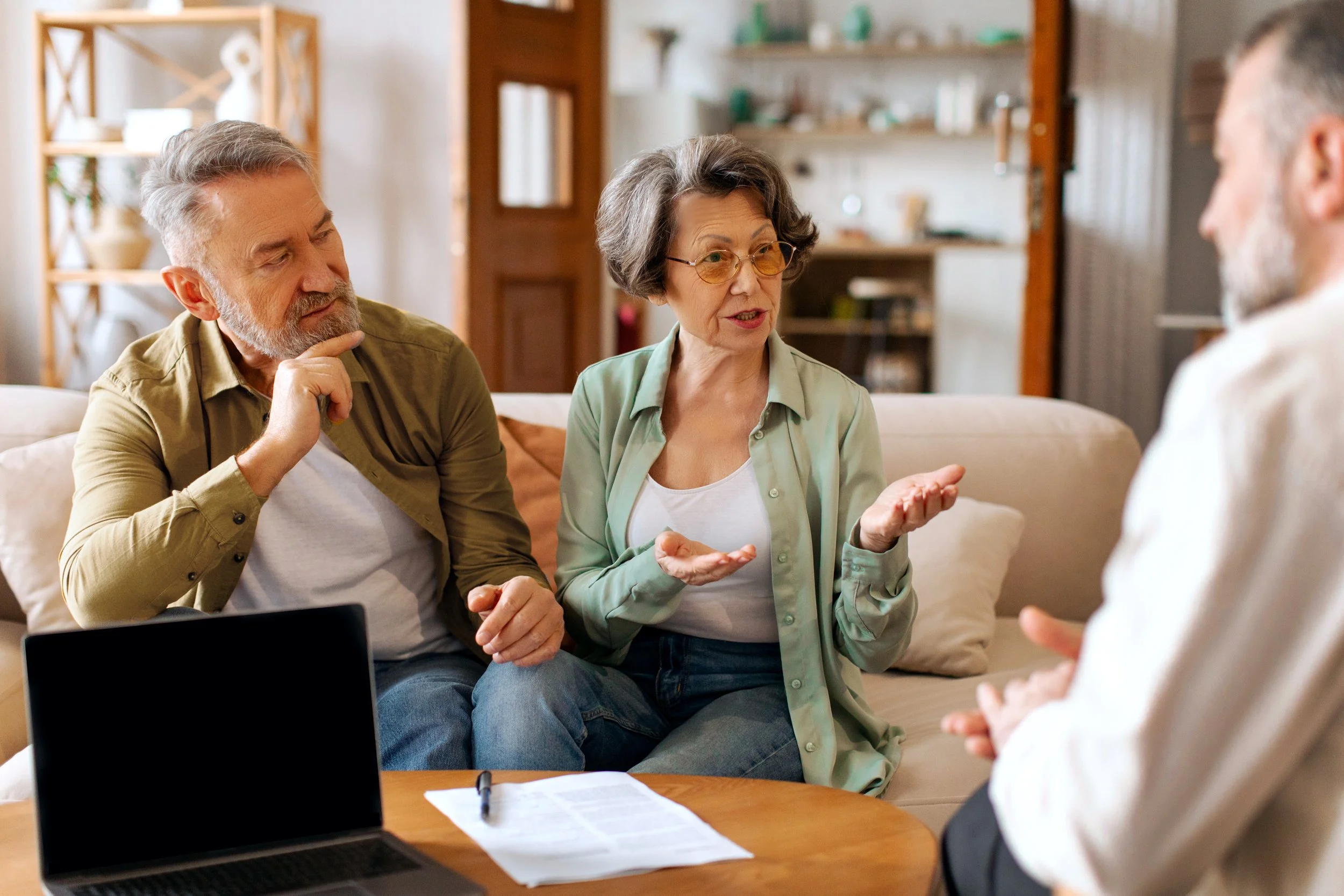 Home sellers discussing offer details and negotiation strategy with a real estate agent in a living room setting in Hudson County, NJ.