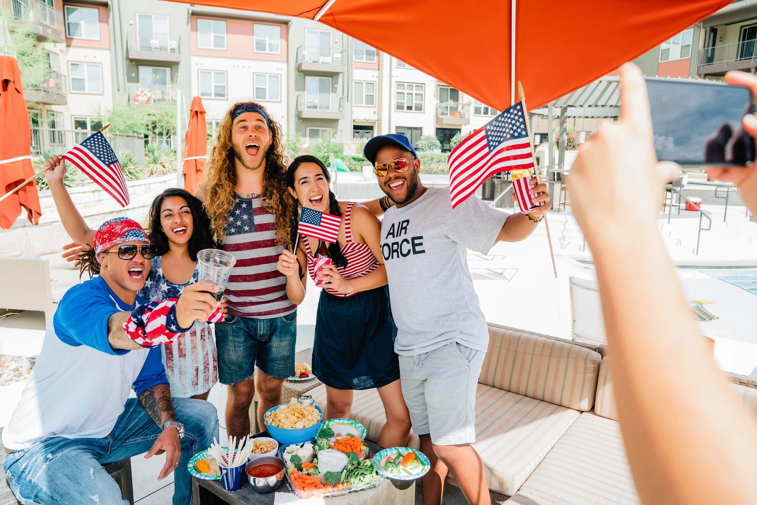 Friends celebrate Independence Day with American flags and food at an outdoor gathering ahead of Fourth of July festivities.