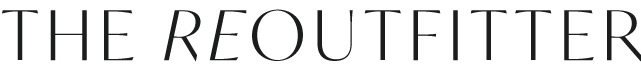 Close-up of a black sign with the text 'The Reoutfitter' in gray and white letters.