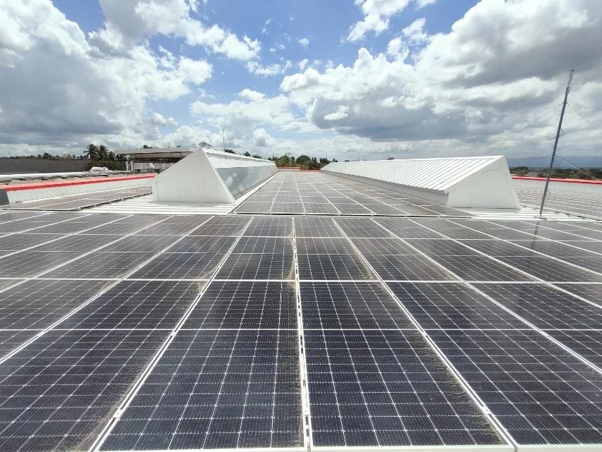 Rooftop solar panels under a partly cloudy sky.