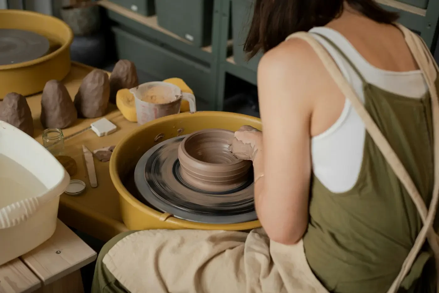 Hands shaping clay on a pottery wheel during a creative workshop, building momentum through small tests and real-world practice