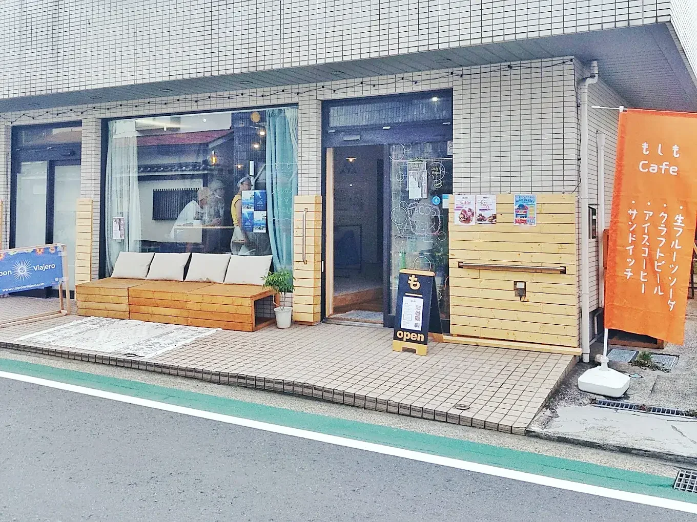 Moshimo Cafe storefront in Hayama, Japan with outdoor bench seating, open sign, and orange cafe banner