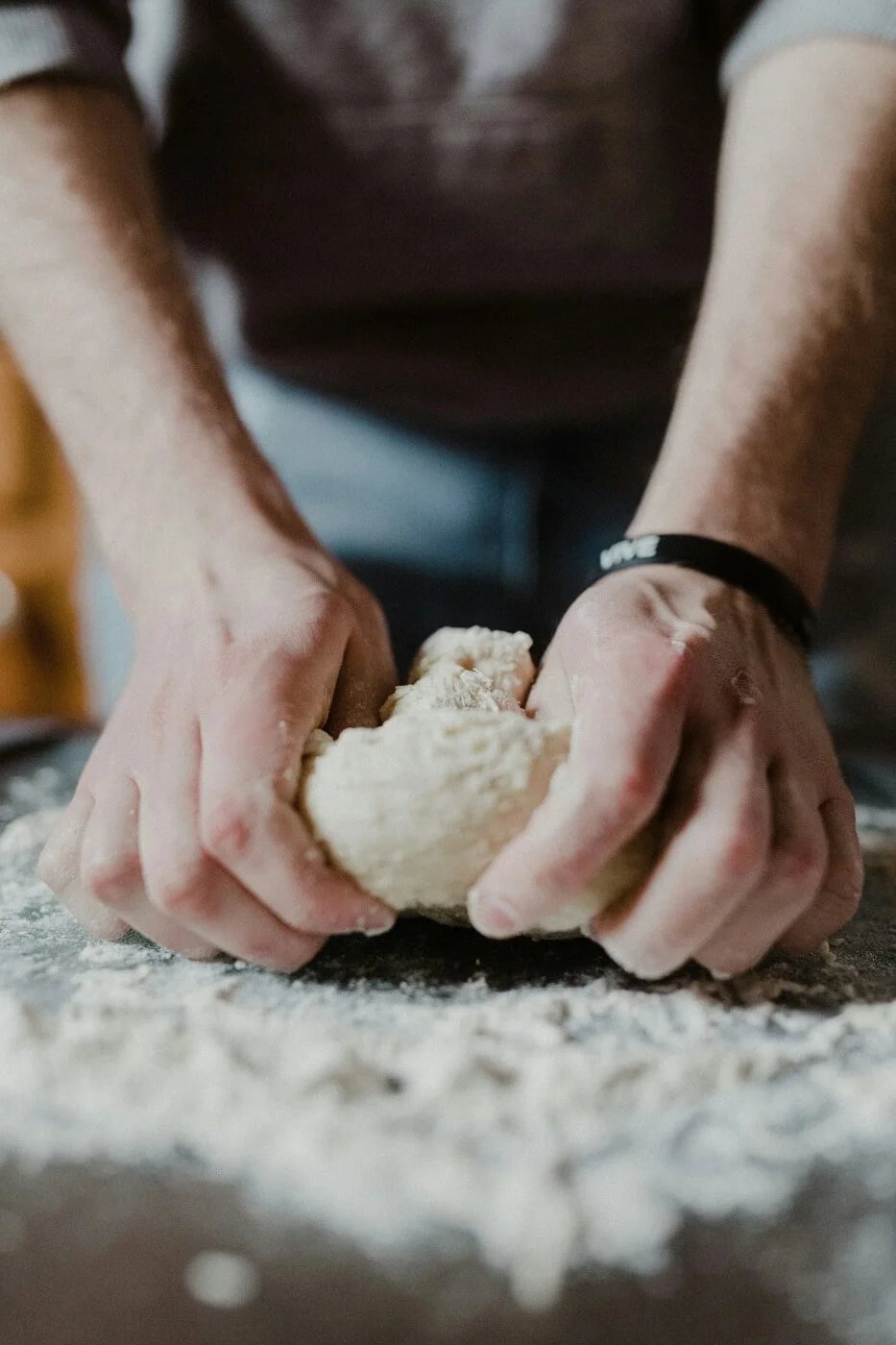 Close-up of hands kneading dough on a floured surface, symbolizing hands-on creative practice that helps rebuild focus and reduce burnout.