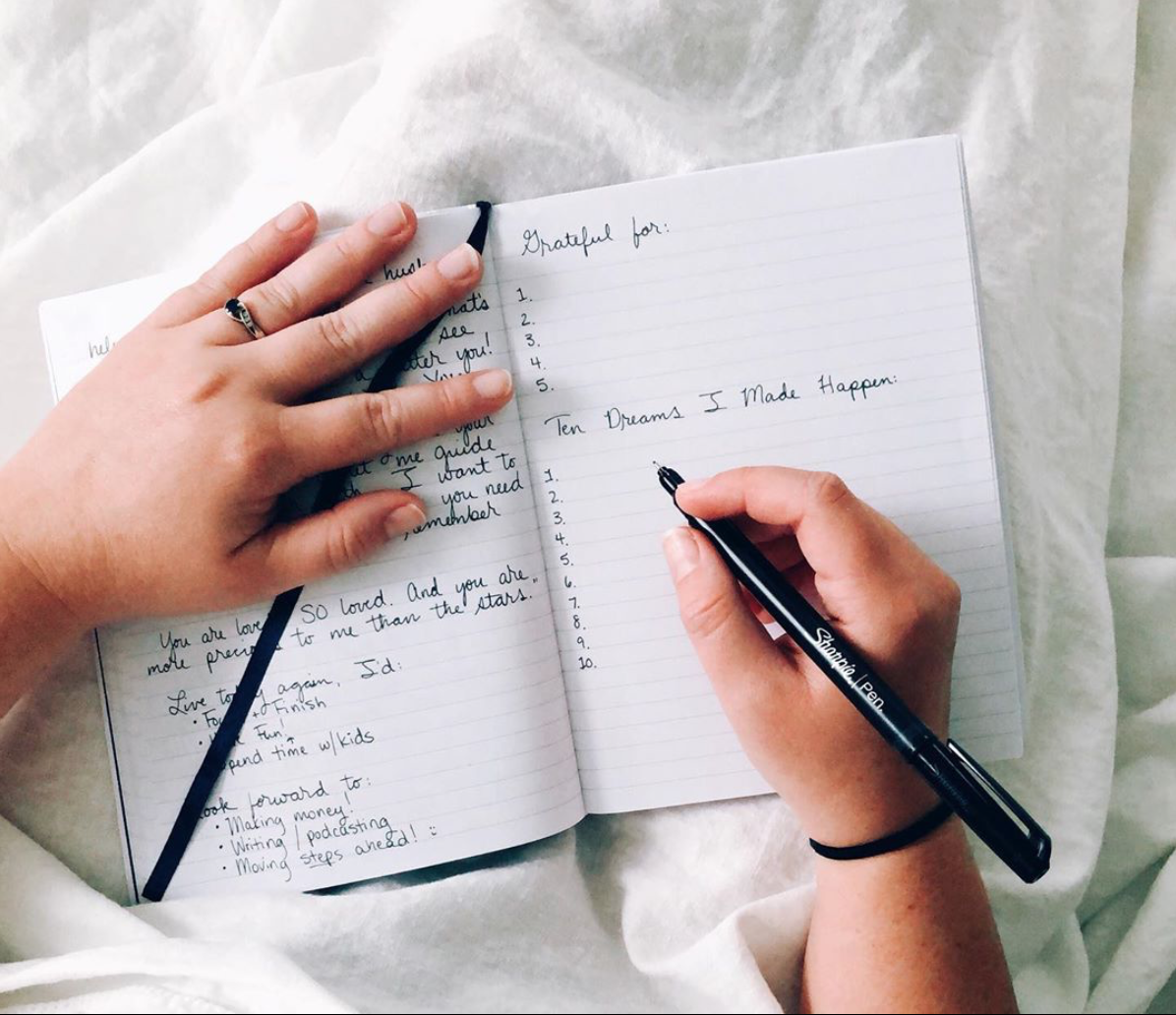 Hand writing daily journaling prompts in a personal journal