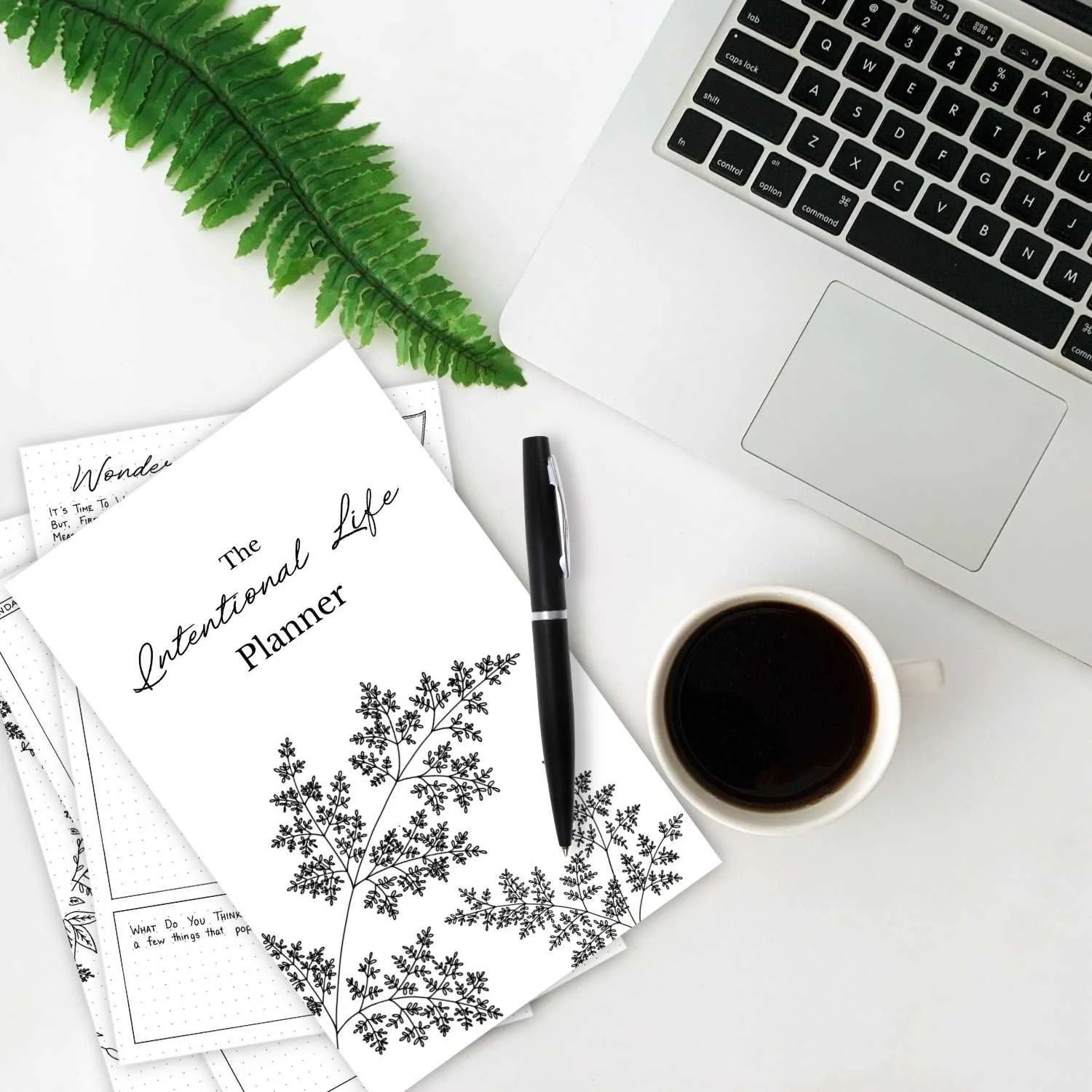 Intentional Life Planner printable PDF shown in a styled flat lay with fern artwork, coffee, and laptop for a cozy planning aesthetic