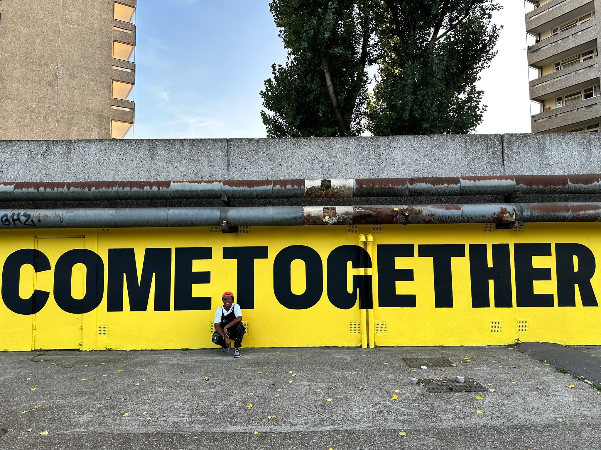  70m long mural commissioned by Peabody for Thamesmead Street Art Trail. The mural reads ‘ People of all cultures and creeds, come together and create the future that Thamesmead needs.’ 