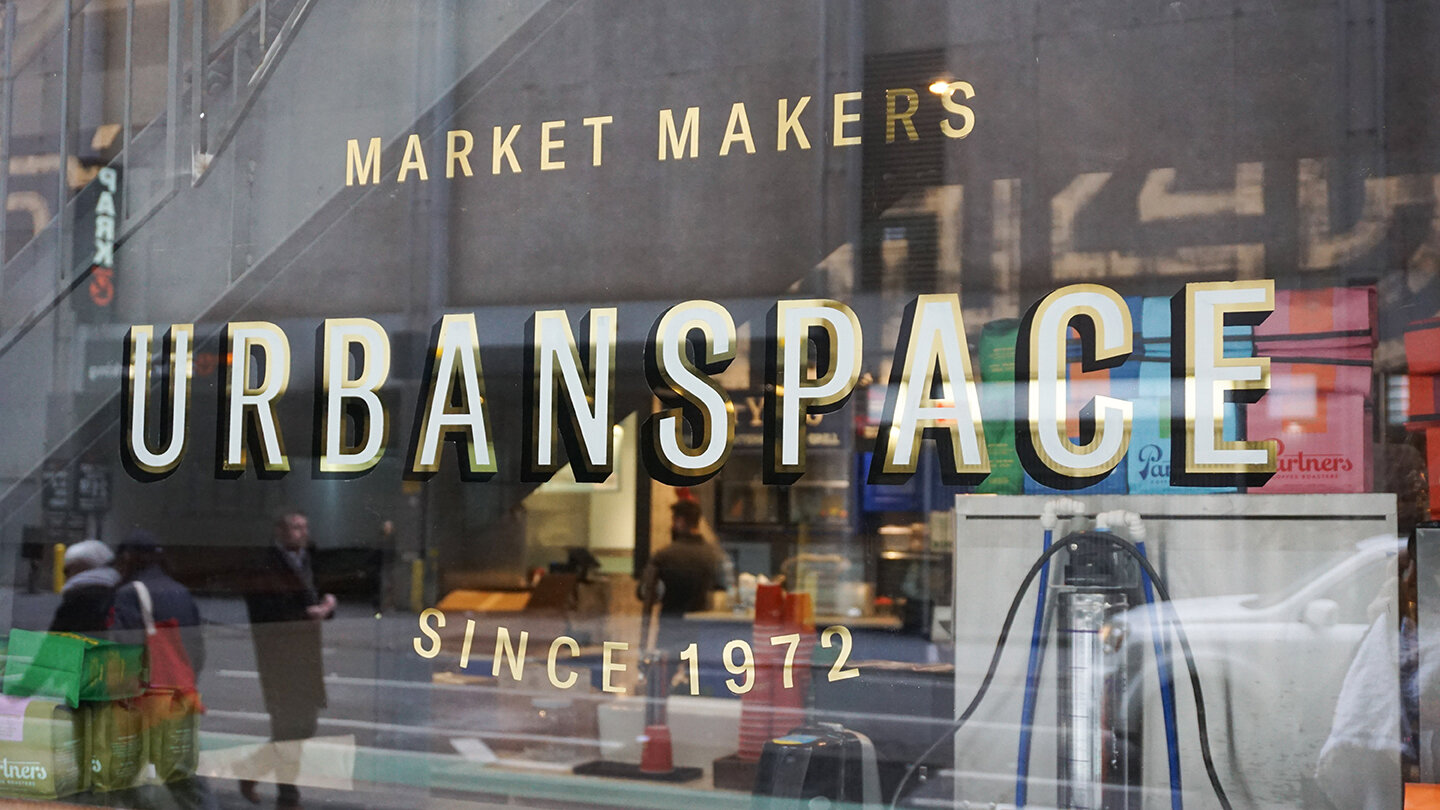 Reflective window gild reading “Market Makers Urbanspace” in sans serif lettering 