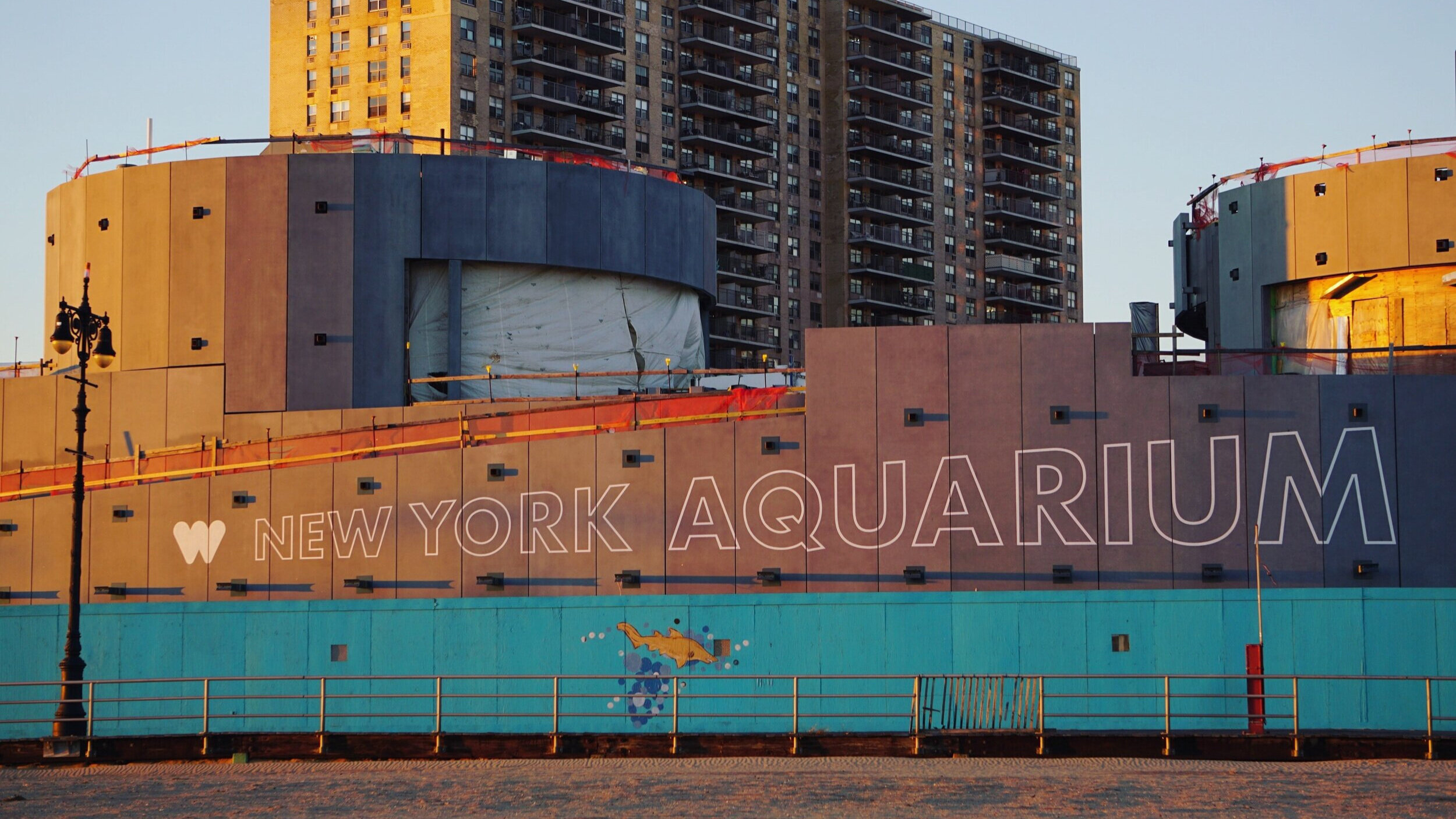  White outlined block lettering reading “NY Aquarium” handpainted onto the side of the aquarium’s exterior wall. 