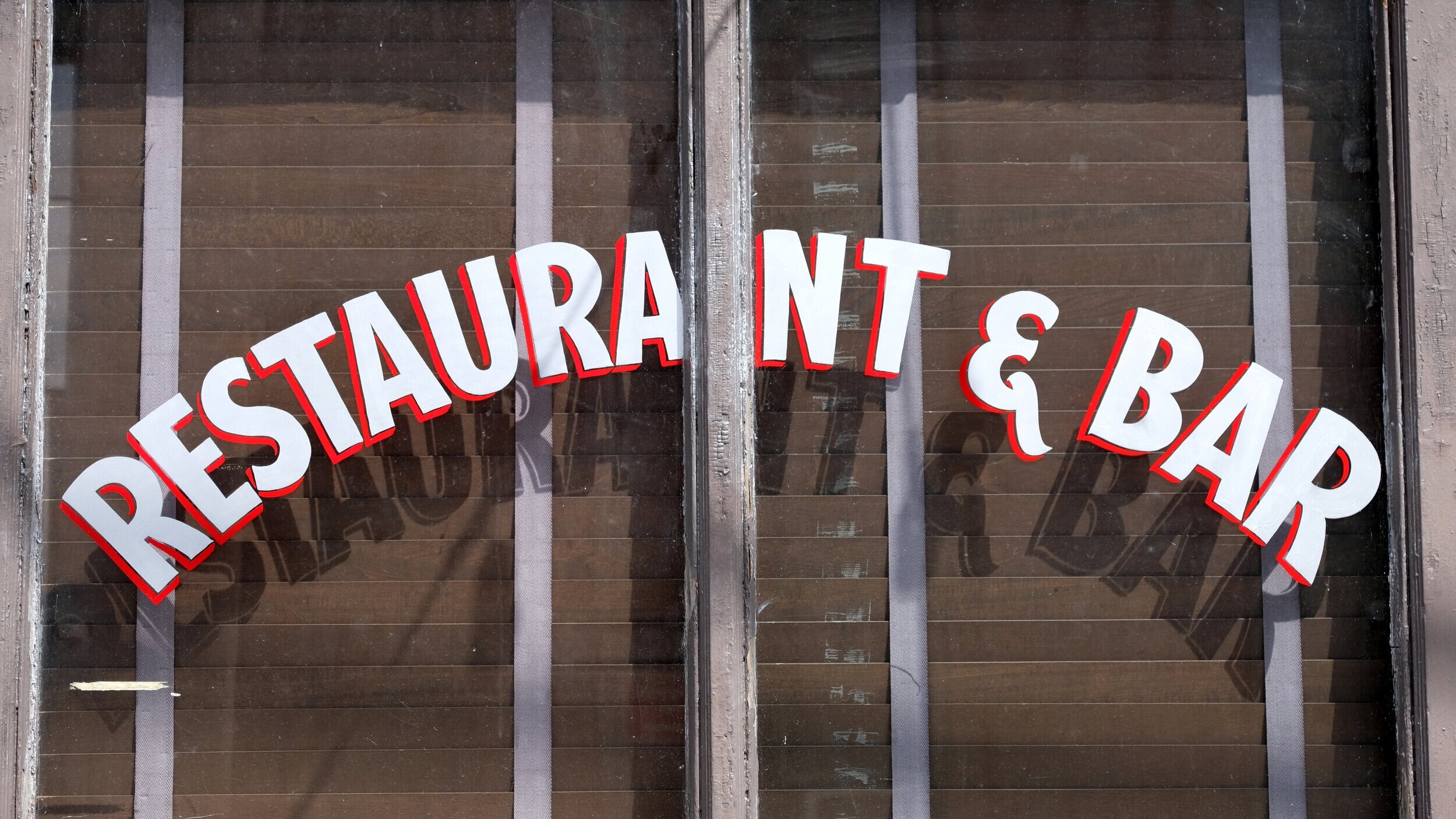  Handpainted window signage with white block lettering with red drop shadow, set at an arc 