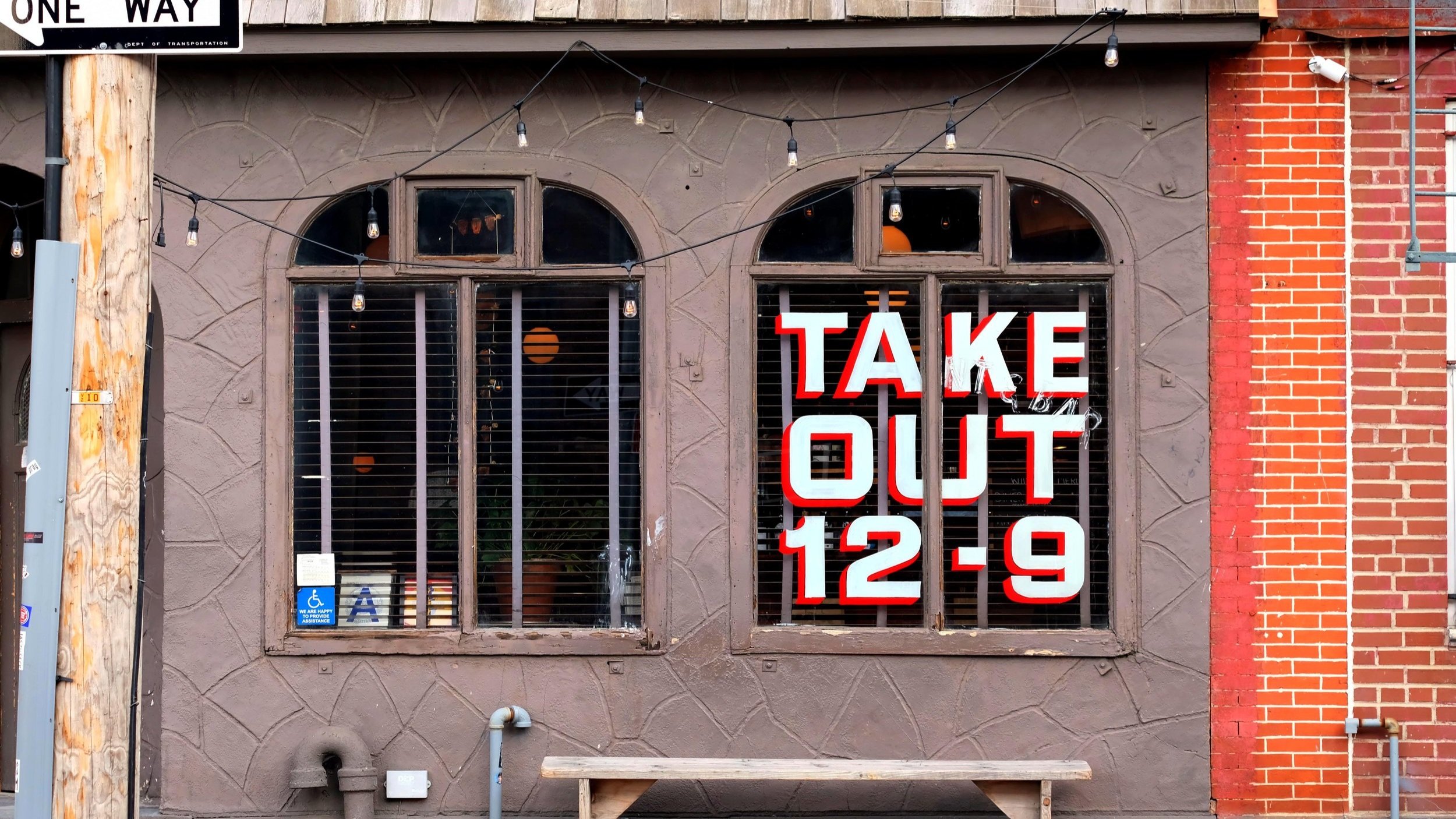  Handpainted sign reading “Take Out 12-9” on set of windows in white block lettering with red drop shadow 