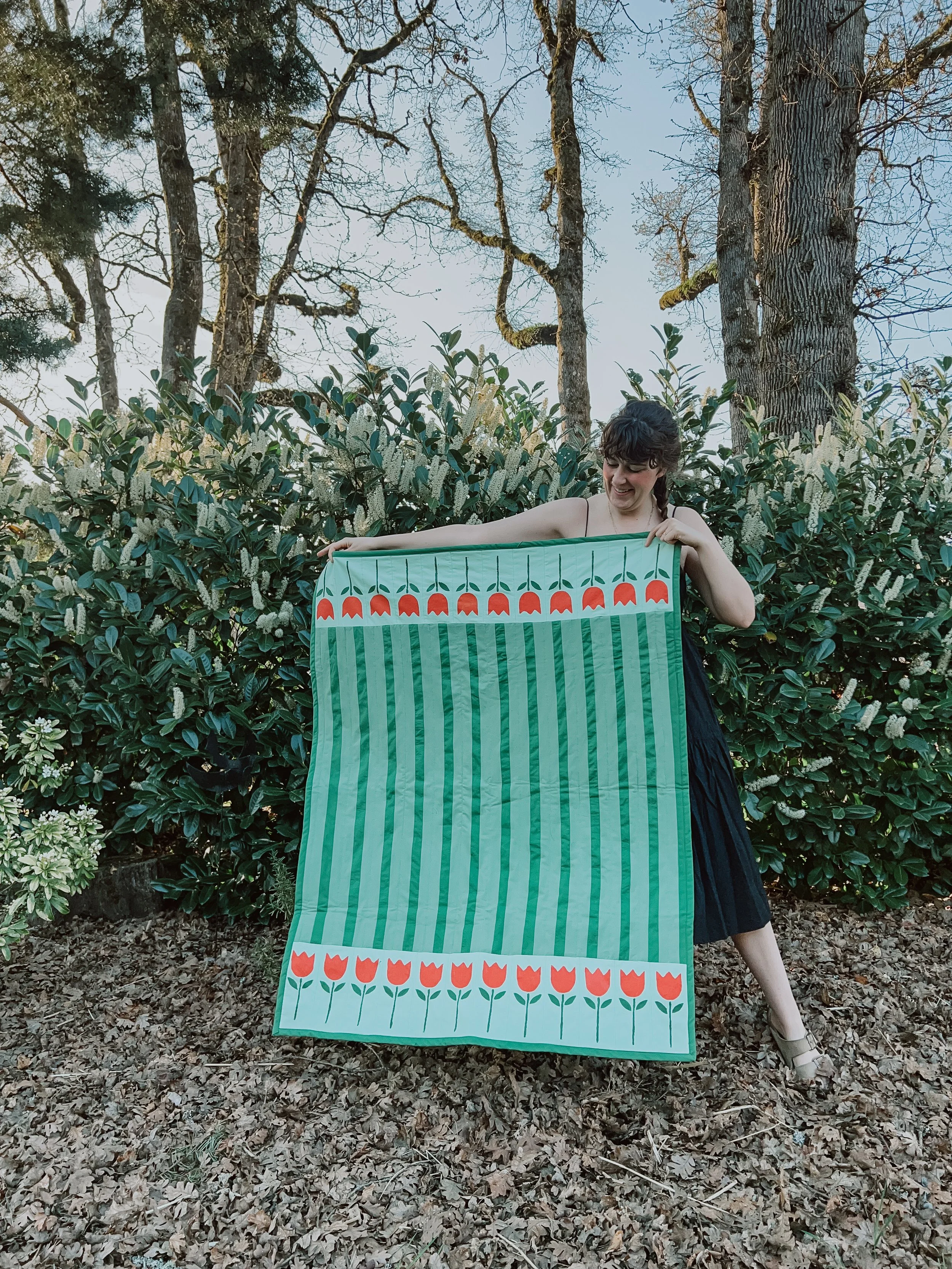 Woman standing in garden holding crib quilt