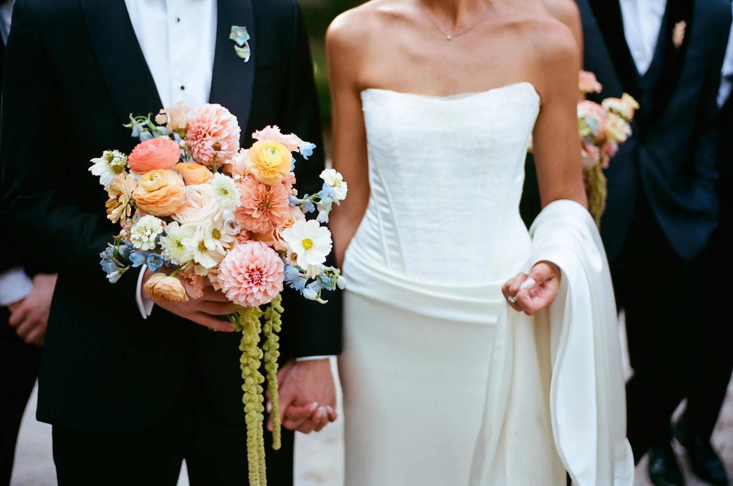 35mm film wedding photograph by Chicago wedding photographer Chandler Austin featuring a bride and groom holding hands with a colorful bouquet, captured in a timeless documentary style