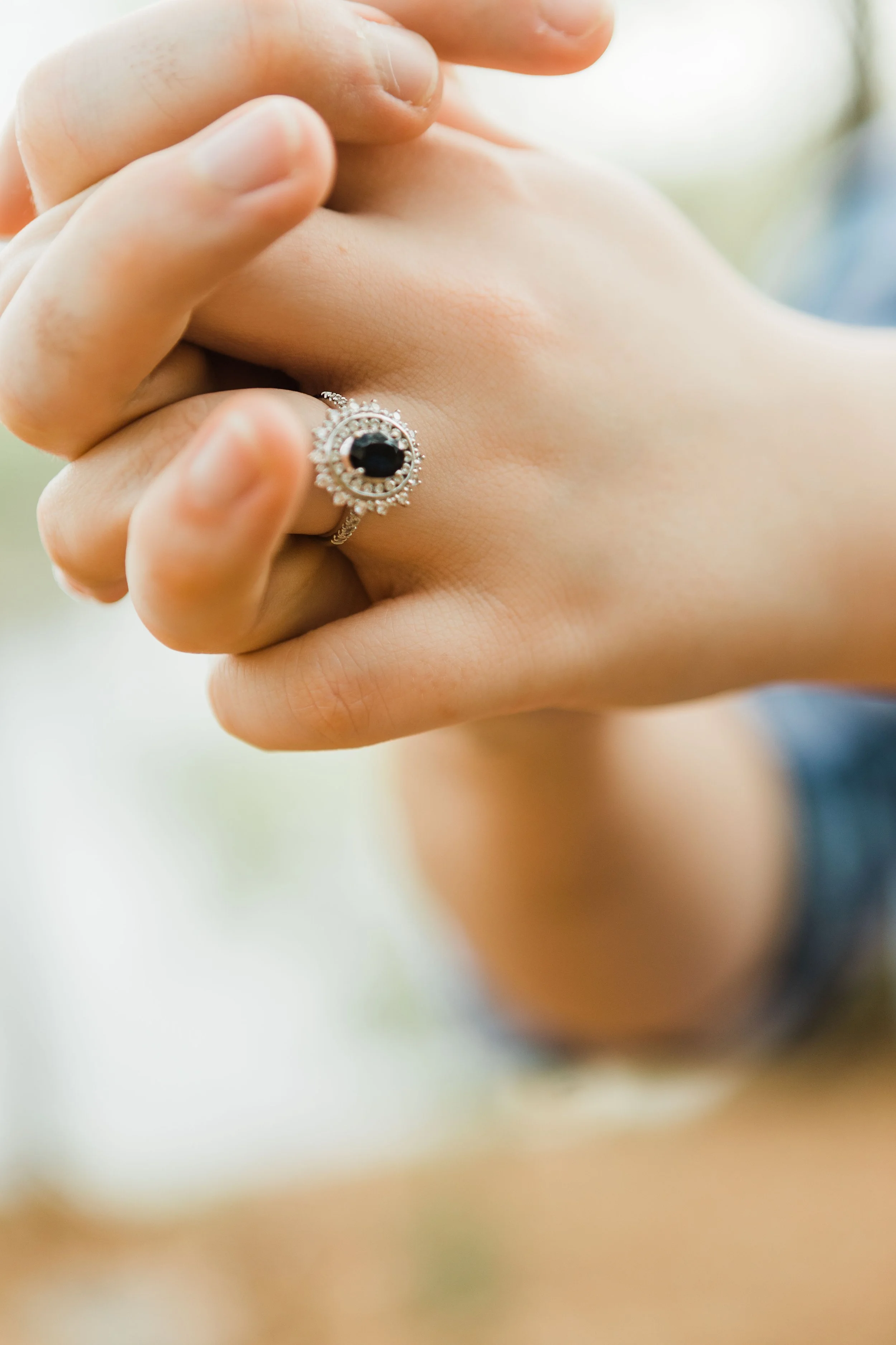 Close-up of a person's hand with a silver ring featuring a black gemstone.