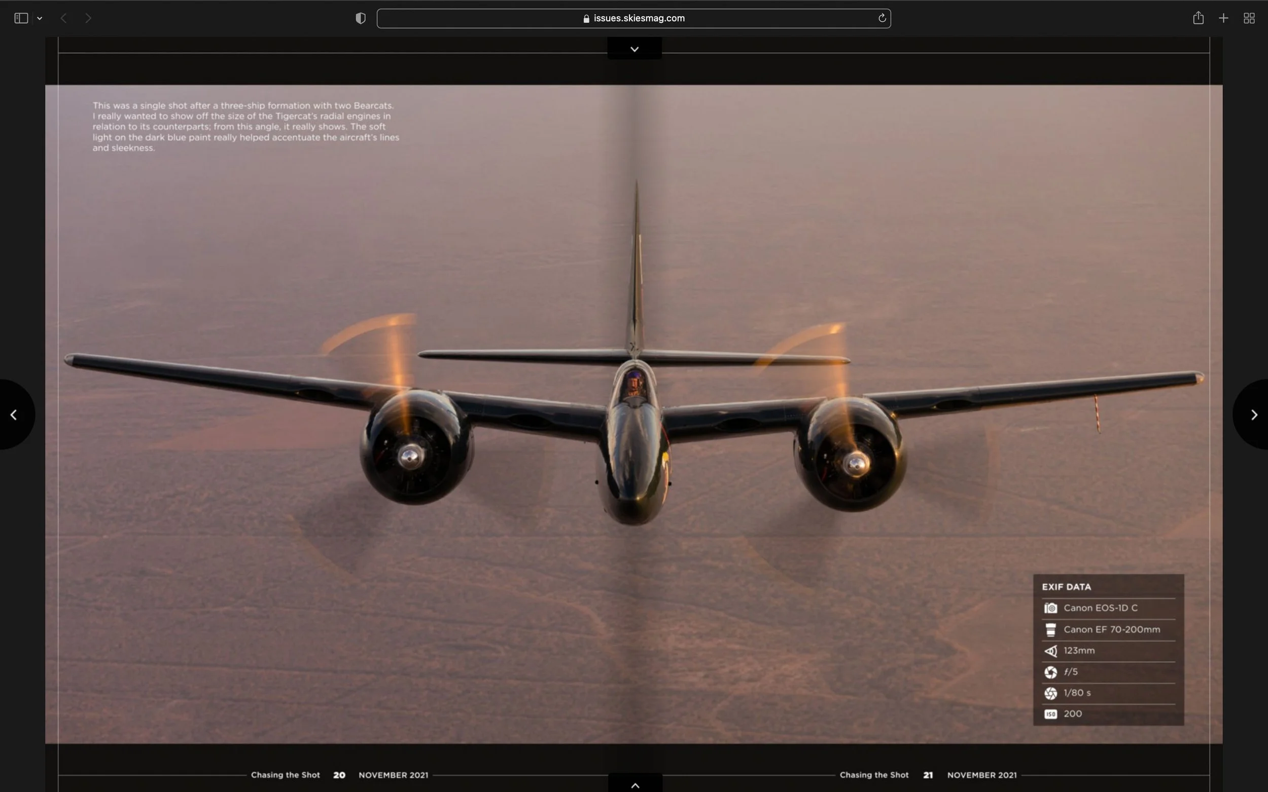 Front view of a dark blue twin-engine aircraft flying over a landscape at sunset. The propellers are spinning, creating a blur effect. Text and camera settings are overlaid on the image.