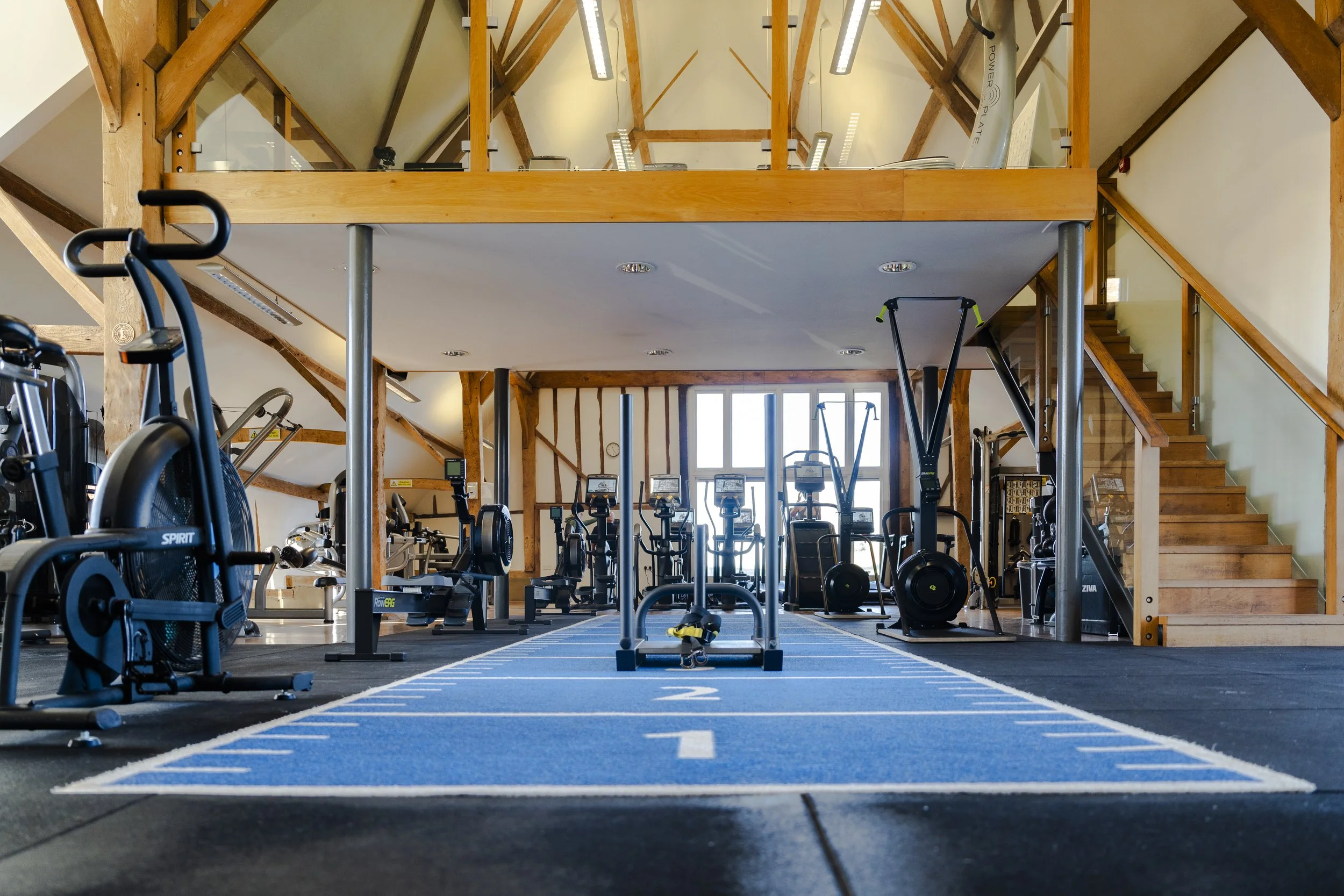 Empty Gym with the latest equipment on show with a blue track in the centre of the gym in the Oxfordshire countryside for a Commercial Photography