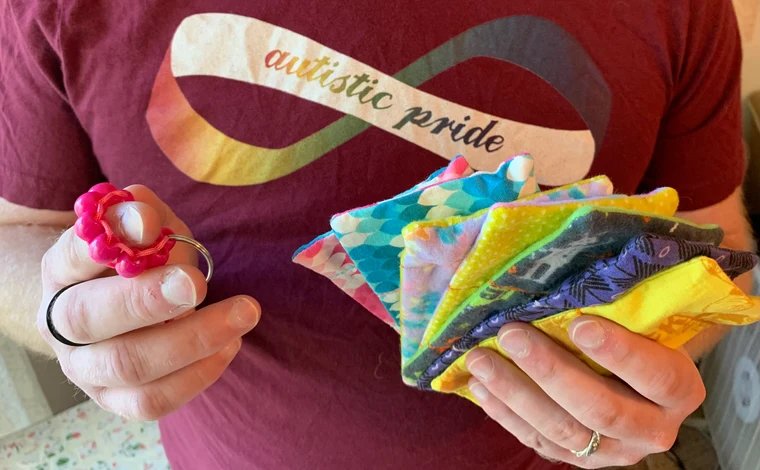 Person holding fidgets and wearing autistic pride shirt