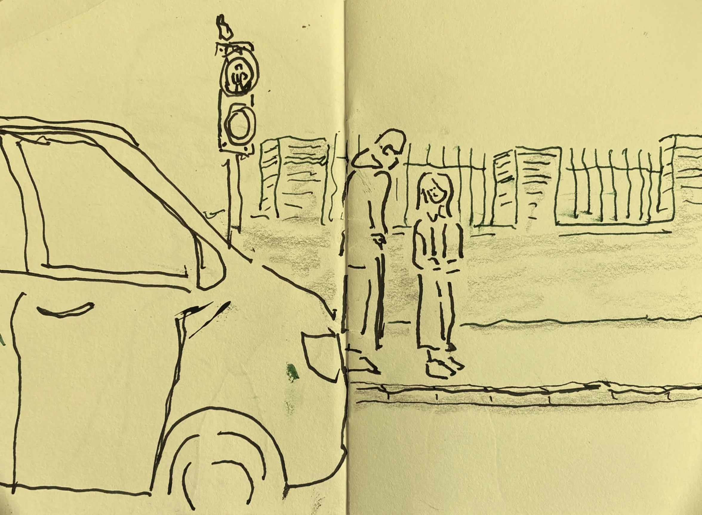 Pen-and-ink sketch of two figures standing at a pedestrian crossing beside a car, traffic lights above, light green fencing in the background.