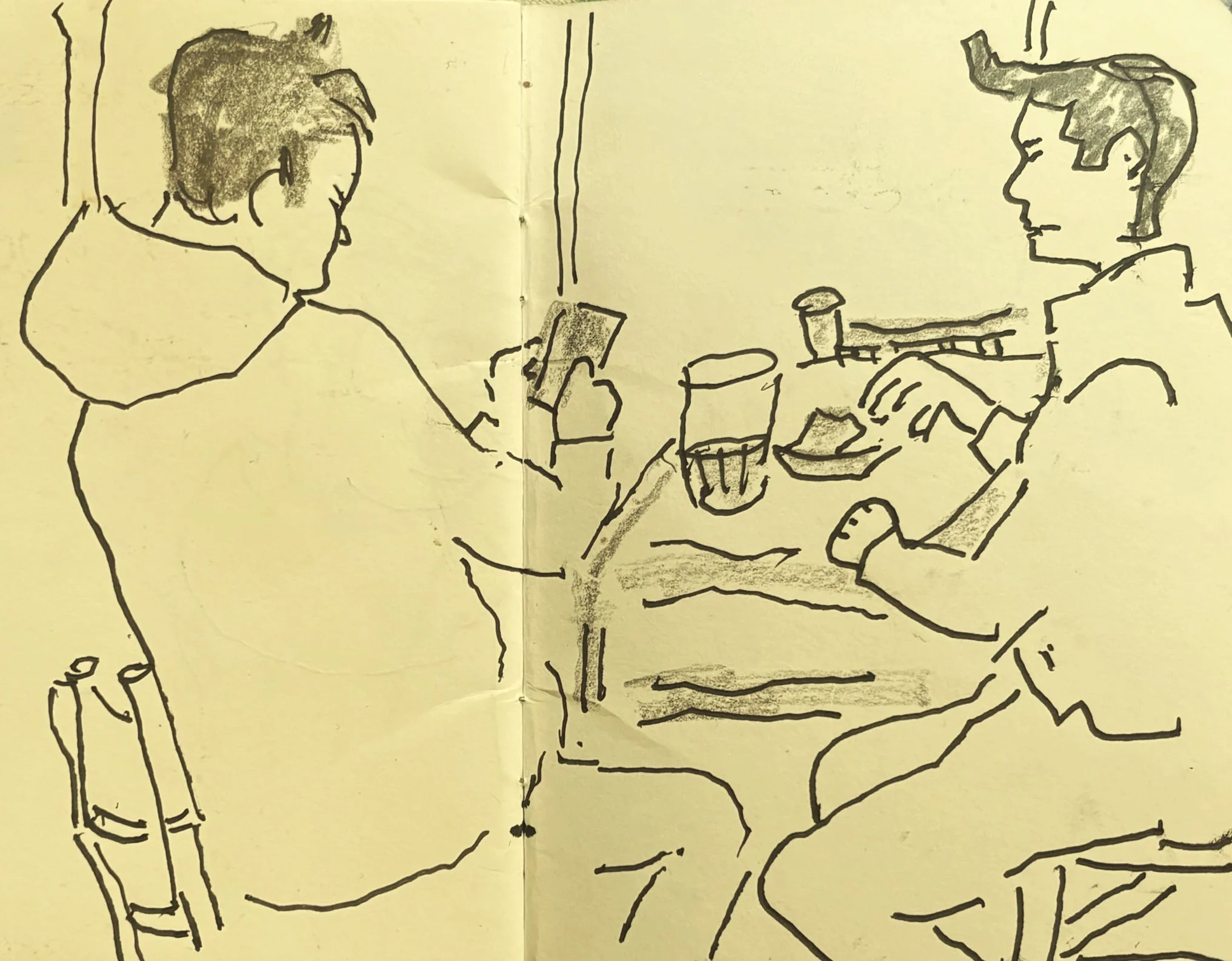 Sketch of two people sitting at a table with drinks, in conversation