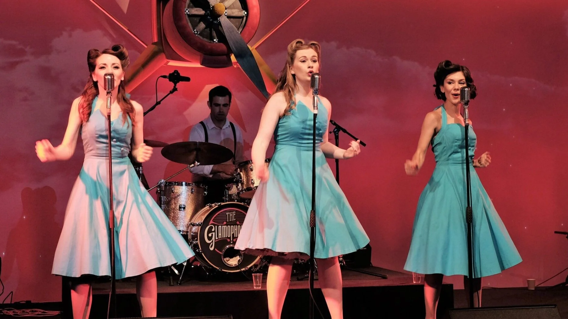 Three singers performing onstage, photographed at a travel industry company event in Birmingham