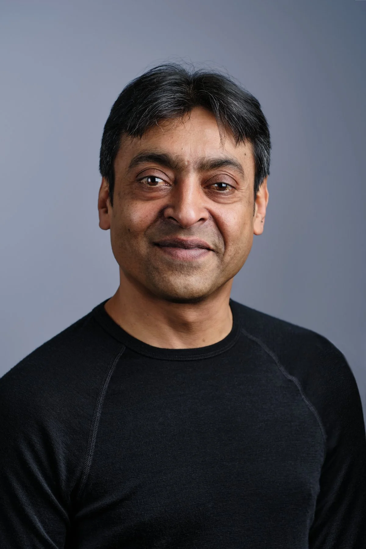 Professional headshot photo of a man in a black top