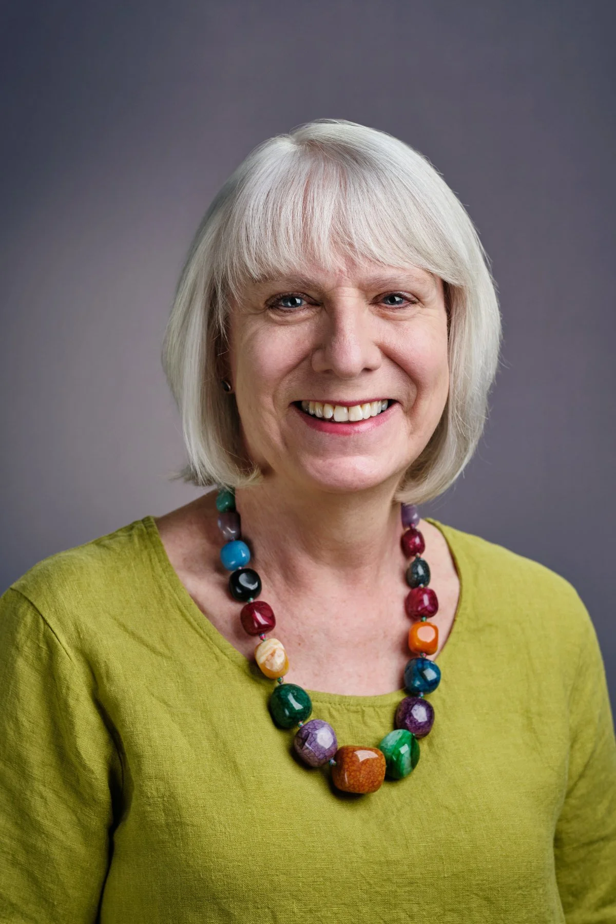 Professional headshot photo of a woman in a green top