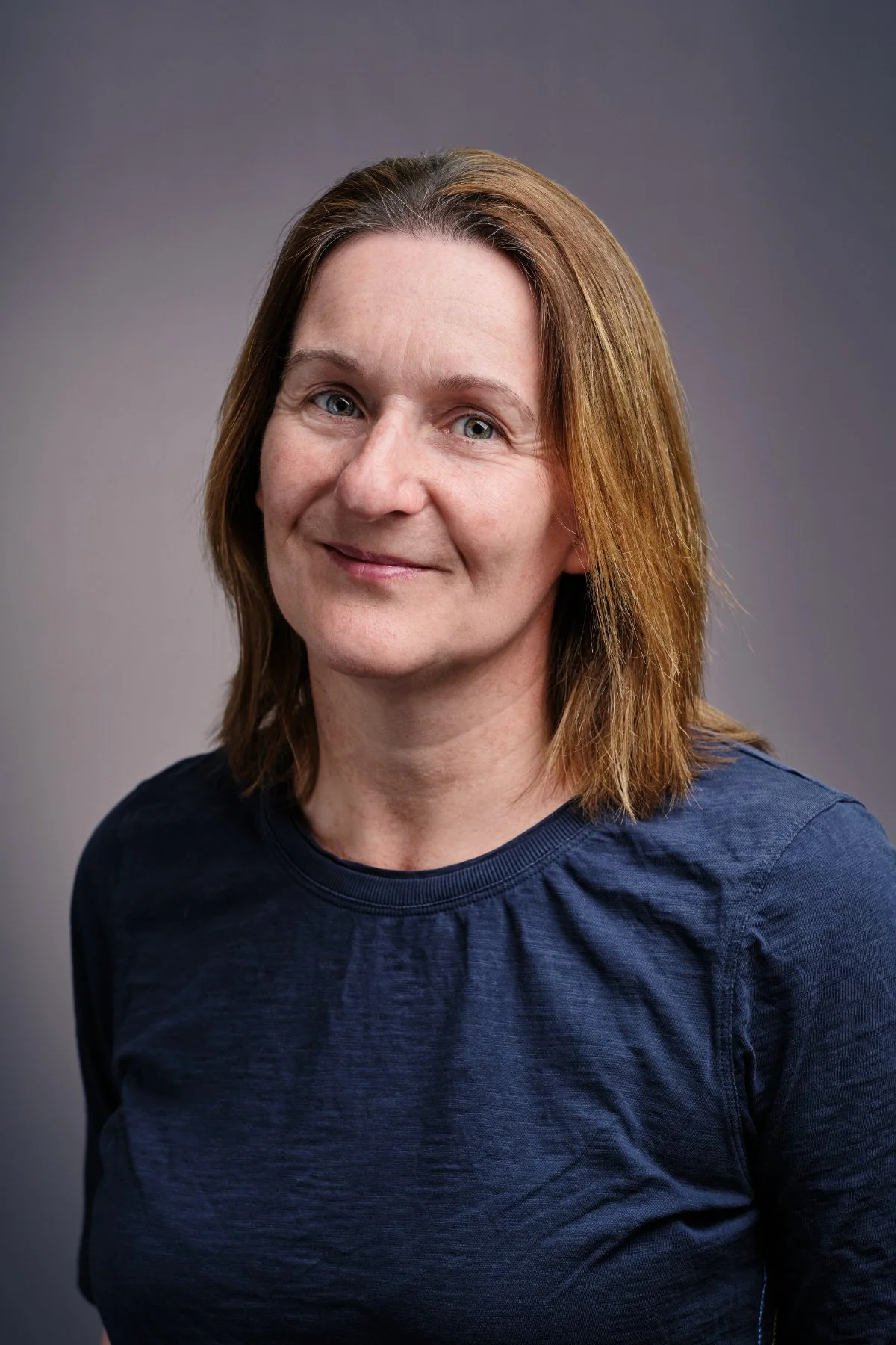 Professional headshot photo of a woman in a dark blue top