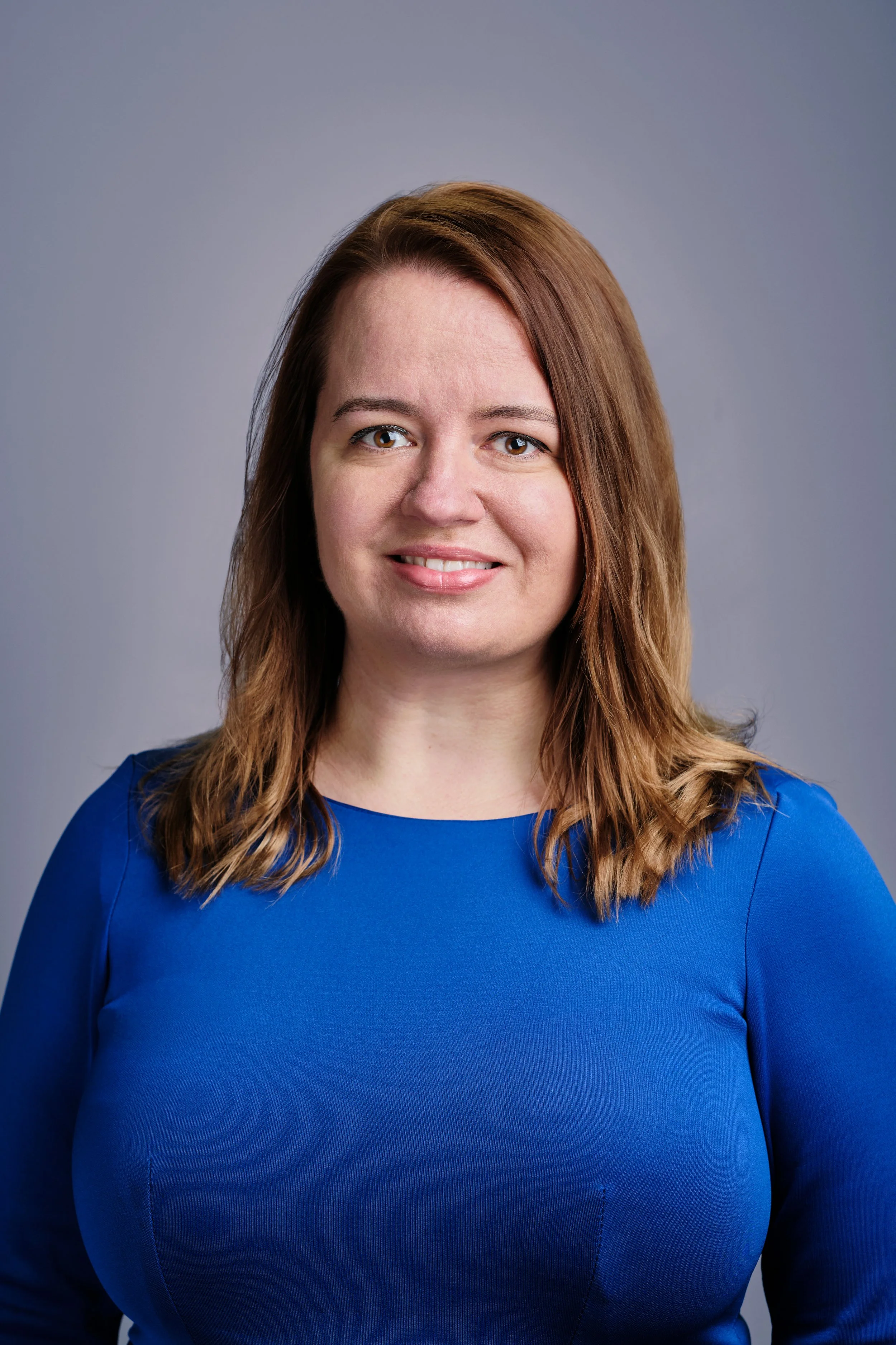 Professional headshot photo of a woman in a blue dress