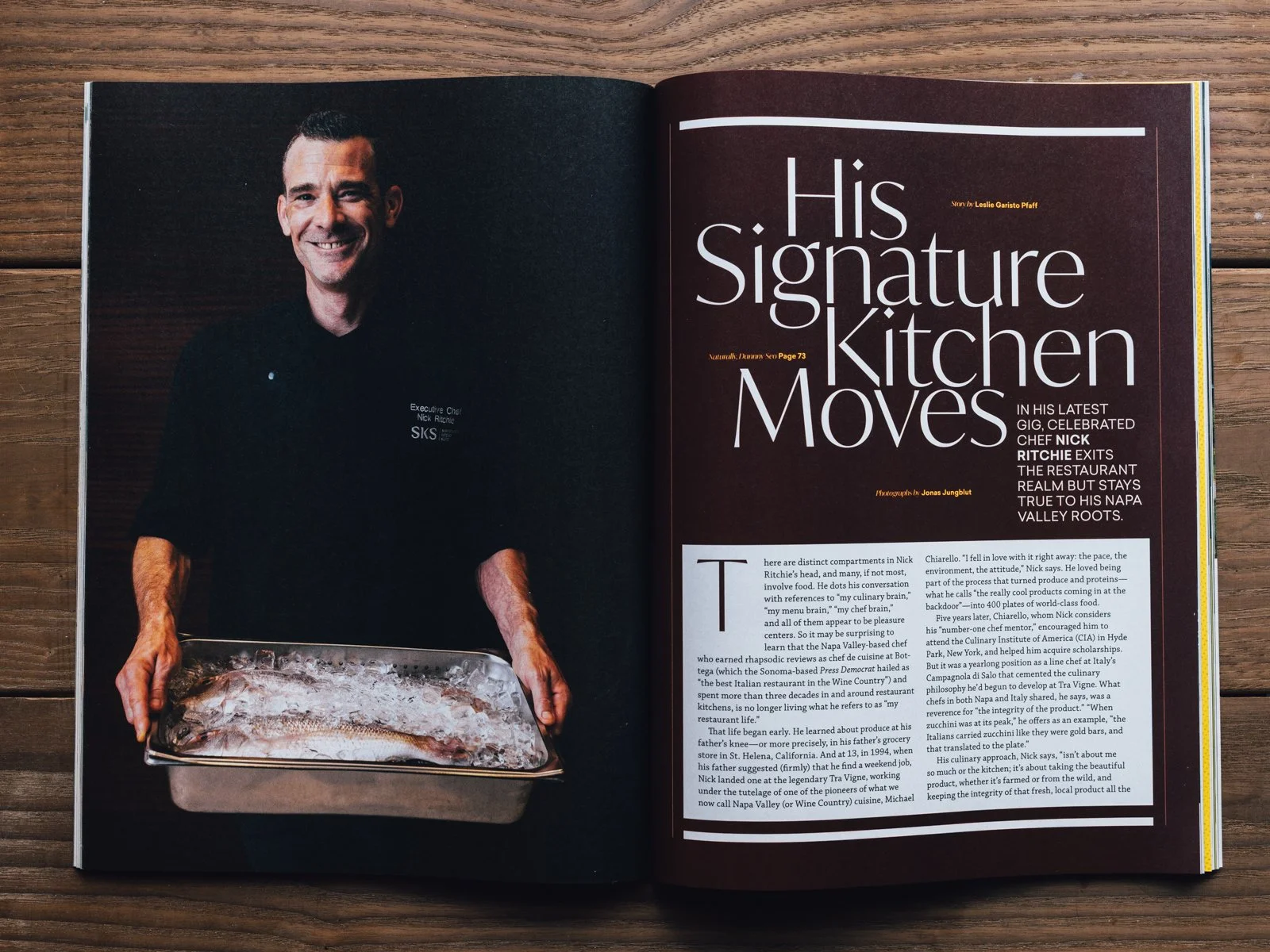 Open magazine spread featuring a portrait of a chef in a black uniform holding a tray with a whole fish on ice on the left page, and an article titled "His Signature Kitchen Moves" by Leslie Garisto Pfaff, with a large headline, subhead, and text on 